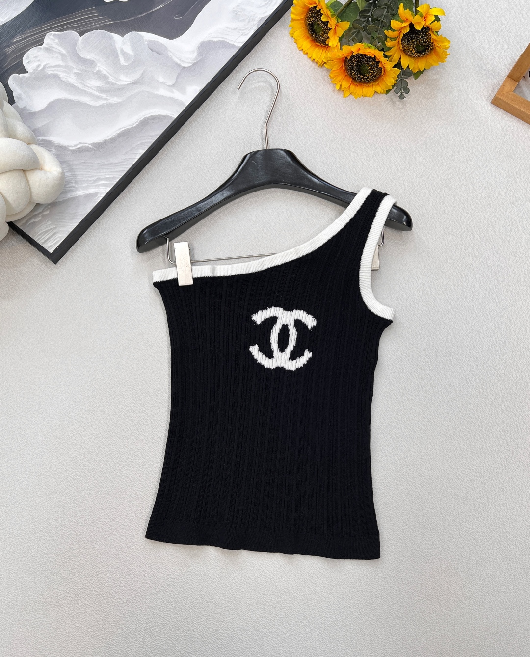 NO:449364,CHANEL2025 new logo jacquard slanted shoulder knit vest, customized YB wool yarn wool, comfortable and soft, full of elasticity, off-shoulder knit vest style, single side off-shoulder neckline, vertical pit strip texture is wrapped in contrasting colors to improve skin exposure and make it look slim and sexy. The design is rich in layering. The iconic logo logo is embellished on the chest to highlight the brand's high-end style, comfortable and elastic, adding retro charm to the outfit. No need to deliberately add decoration to show the fashionable outfit. Fashionable Hong Kong style, customized surface accessories, accurate version, high version, 2 colors, complete three standards!  Size sml code, chanel,alexander wang19860909CHANEL2025新款logo提花斜肩针织背心,定制YB羊毛纱线织造 舒适软糯 弹力十足 斜肩针织背心版型 单侧斜肩领口 竖坑条肌理以撞色包边包裹固定 提升露肤度显瘦性感 设计层次感丰富 胸前位置点缀标志性logo标 彰显品牌高级格调 舒适有弹力 为穿搭增添复古魅力 无需刻意加饰 即可彰显穿搭洋气感 时髦港风 定制面辅料 认准版本 高版本 2色出,三标齐全！ 尺码sml 编码,,chanel,alexander wang,Women's clothing