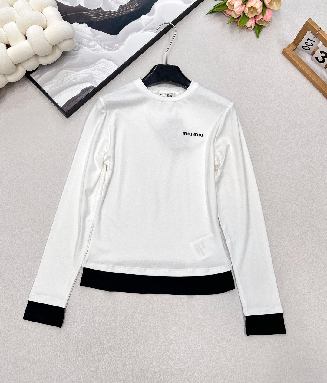 NO:463822,MIU MIU autumn and winter new color-blocking side-fake two-piece long-sleeved T-shirt This color-blocking side-fake two-piece long-sleeved T-shirt is full of love!  The simple white body, paired with classic black edges, cleverly creates a fake two-piece visual effect, a fashionable feeling up!  The exquisite brand logo on the chest shows quality and style in a low-key manner. The slim waist-hugging style easily outlines the graceful figure, which is perfect for both single wear and as an inner wear~ The elastic and soft fabric is comfortable and comfortable to wear with close body, bringing gentle care to the skin. Whether it is paired with jeans to create a casual style or a skirt to show elegant temperament, it can be easily adapted, adding highlights to your autumn and winter outfits and making you feel different in this season!  Complete three standards, large-scale goods, size sml code M,,miumiu, skirts, jeans,tees, t-shirt,alexander wang19860909MIU MIU秋冬新款拼色边假两件长袖T恤 这款拼色边假两件长袖T恤,一整个爱住了！ 简约的白色衣身,搭配经典黑边点缀袖口与下摆,巧妙营造出假两件视觉效果,时髦感up up！胸前精致的品牌标识,低调彰显品质与格调. 修身收腰版型,轻松勾勒出曼妙身姿,无论是单穿还是作为内搭都超合适~ 弹力软糯的面料,贴身穿舒适又自在,给肌肤带来温柔的呵护. 无论是搭配牛仔裤打造休闲风,还是与半身裙组合展现优雅气质,它都能轻松适配,为你的秋冬穿搭增添亮点,让你在这个季节时尚不重样！三标齐全,大货出 尺码sml 编码M,,miumiu,skirts,jeans,tees，t-shirt,alexander wang,Women's clothing
