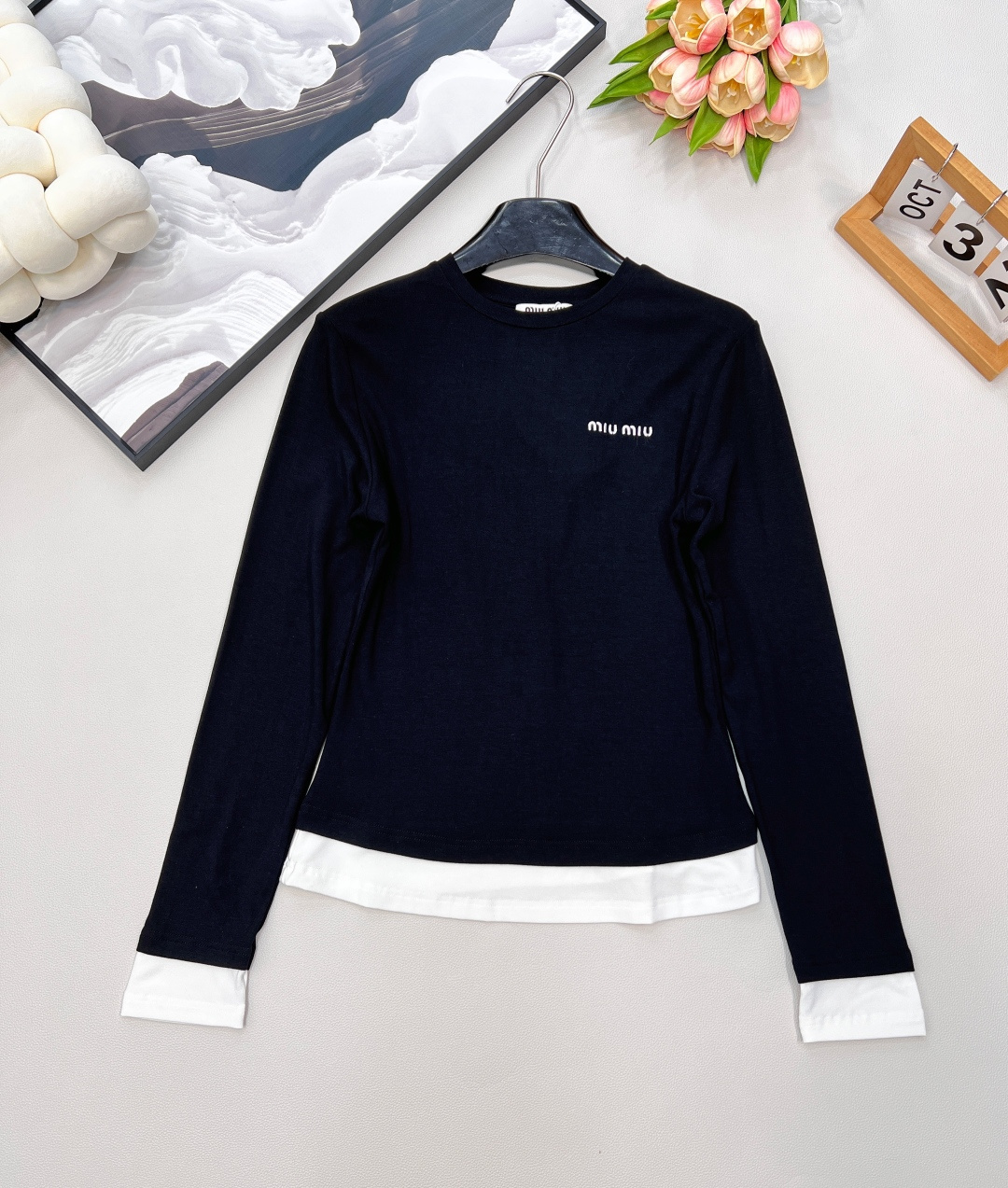 NO:463829,MIU MIU autumn and winter new color-blocking side-fake two-piece long-sleeved T-shirt This color-blocking side-fake two-piece long-sleeved T-shirt is full of love!  The simple white body, paired with classic black edges, cleverly creates a fake two-piece visual effect, a fashionable feeling up!  The exquisite brand logo on the chest shows quality and style in a low-key manner. The slim waist-hugging style easily outlines the graceful figure, which is perfect for both single wear and as an inner wear~ The elastic and soft fabric is comfortable and comfortable to wear with close body, bringing gentle care to the skin. Whether it is paired with jeans to create a casual style or a skirt to show elegant temperament, it can be easily adapted, adding highlights to your autumn and winter outfits and making you feel different in this season!  Complete three standards, large-scale goods, size sml code, miumiu, skirts, jeans, tees, t-shirt, alexander wang19860909MIU MIU秋冬新款拼色边假两件长袖T恤 这款拼色边假两件长袖T恤,一整个爱住了！ 简约的白色衣身,搭配经典黑边点缀袖口与下摆,巧妙营造出假两件视觉效果,时髦感up up！胸前精致的品牌标识,低调彰显品质与格调. 修身收腰版型,轻松勾勒出曼妙身姿,无论是单穿还是作为内搭都超合适~ 弹力软糯的面料,贴身穿舒适又自在,给肌肤带来温柔的呵护. 无论是搭配牛仔裤打造休闲风,还是与半身裙组合展现优雅气质,它都能轻松适配,为你的秋冬穿搭增添亮点,让你在这个季节时尚不重样！三标齐全,大货出 尺码sml 编码,,miumiu,skirts,jeans,tees，t-shirt,alexander wang,Women's clothing