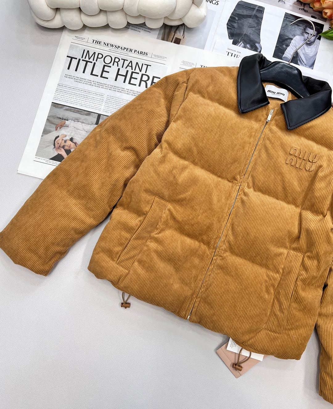 🆕 MIUMIU 暖色灯芯绒皮翻领拉链羽绒服，采用灯芯绒面料，手感柔软细腻，保暖性良好。同时，灯芯绒的表