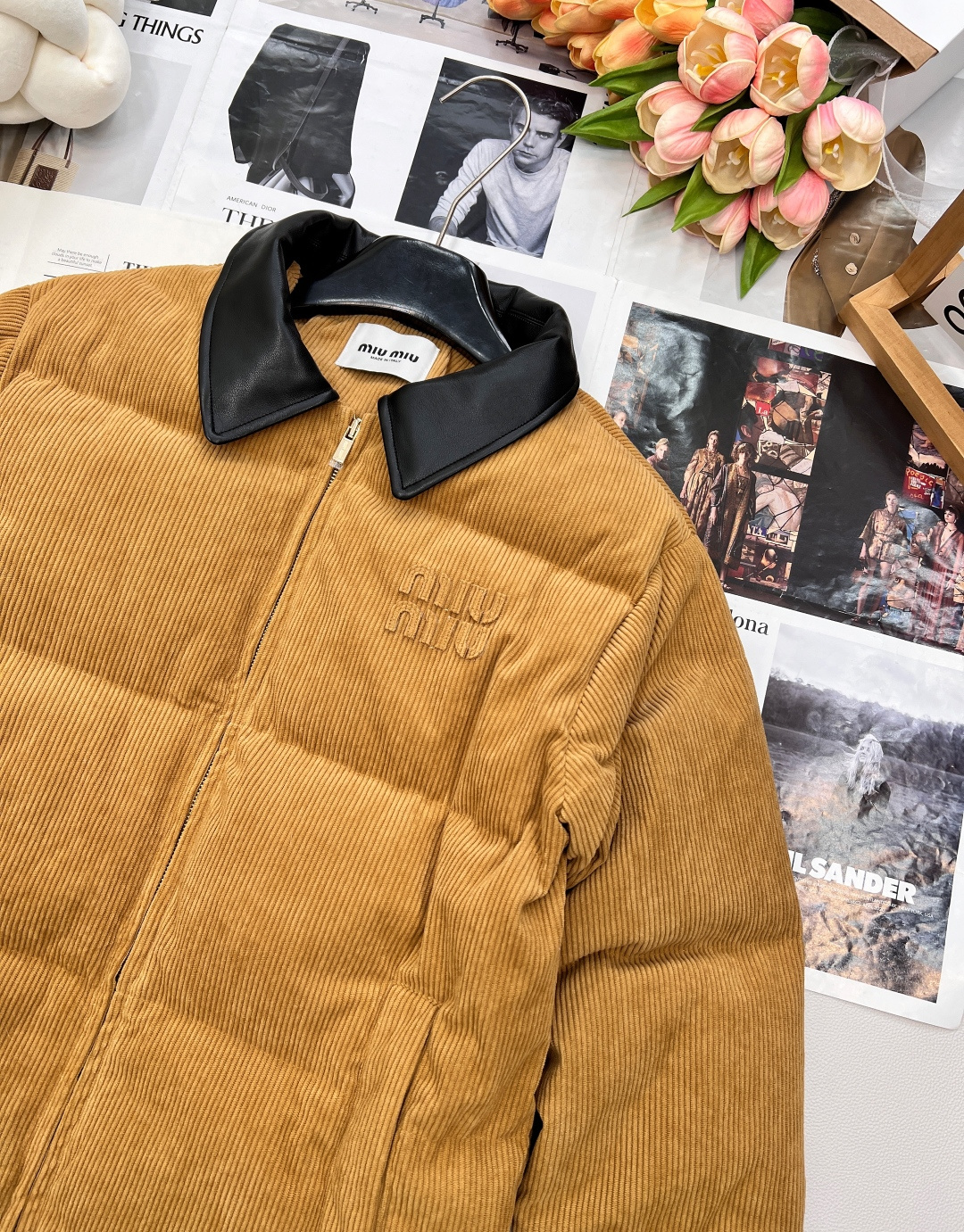 🆕 MIUMIU 暖色灯芯绒皮翻领拉链羽绒服，采用灯芯绒面料，手感柔软细腻，保暖性良好。同时，灯芯绒的表