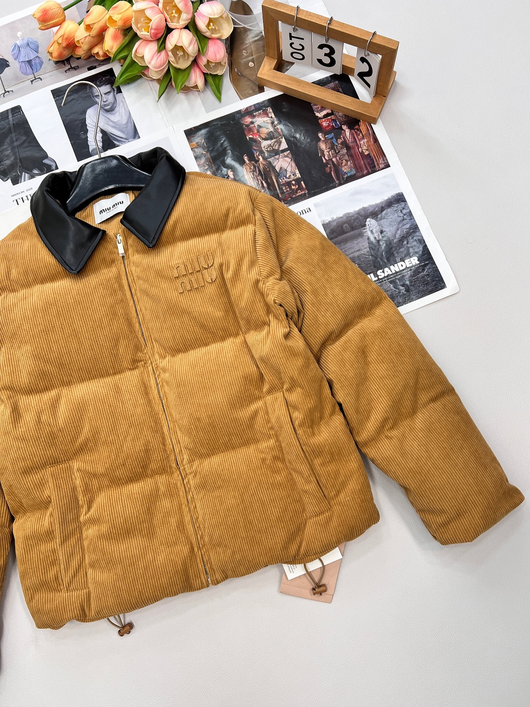 🆕 MIUMIU 暖色灯芯绒皮翻领拉链羽绒服，采用灯芯绒面料，手感柔软细腻，保暖性良好。同时，灯芯绒的表