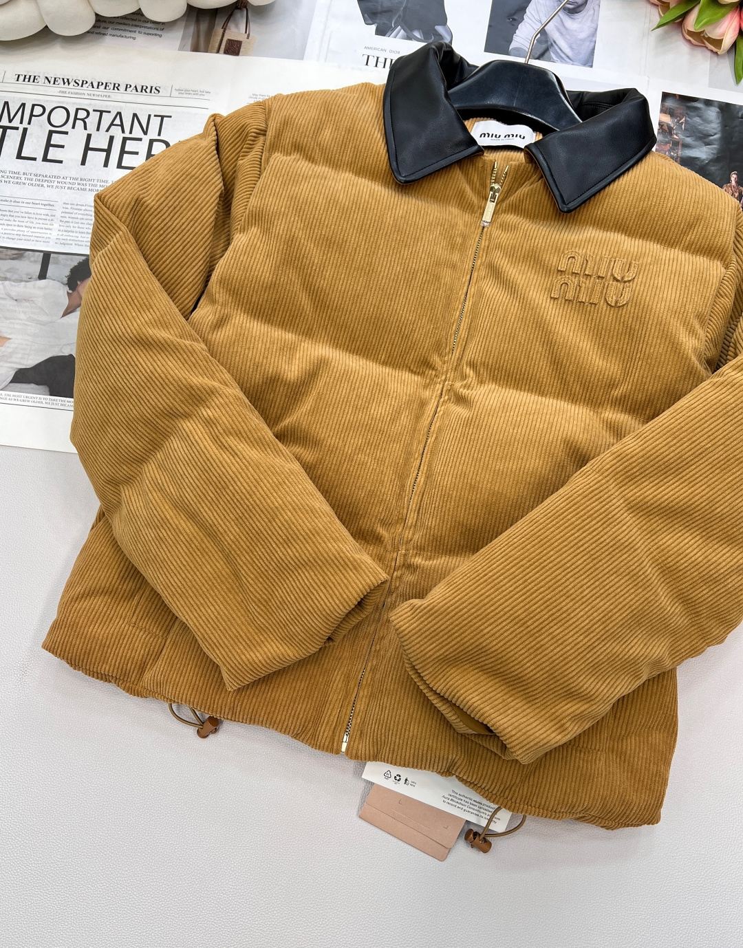 🆕 MIUMIU 暖色灯芯绒皮翻领拉链羽绒服，采用灯芯绒面料，手感柔软细腻，保暖性良好。同时，灯芯绒的表