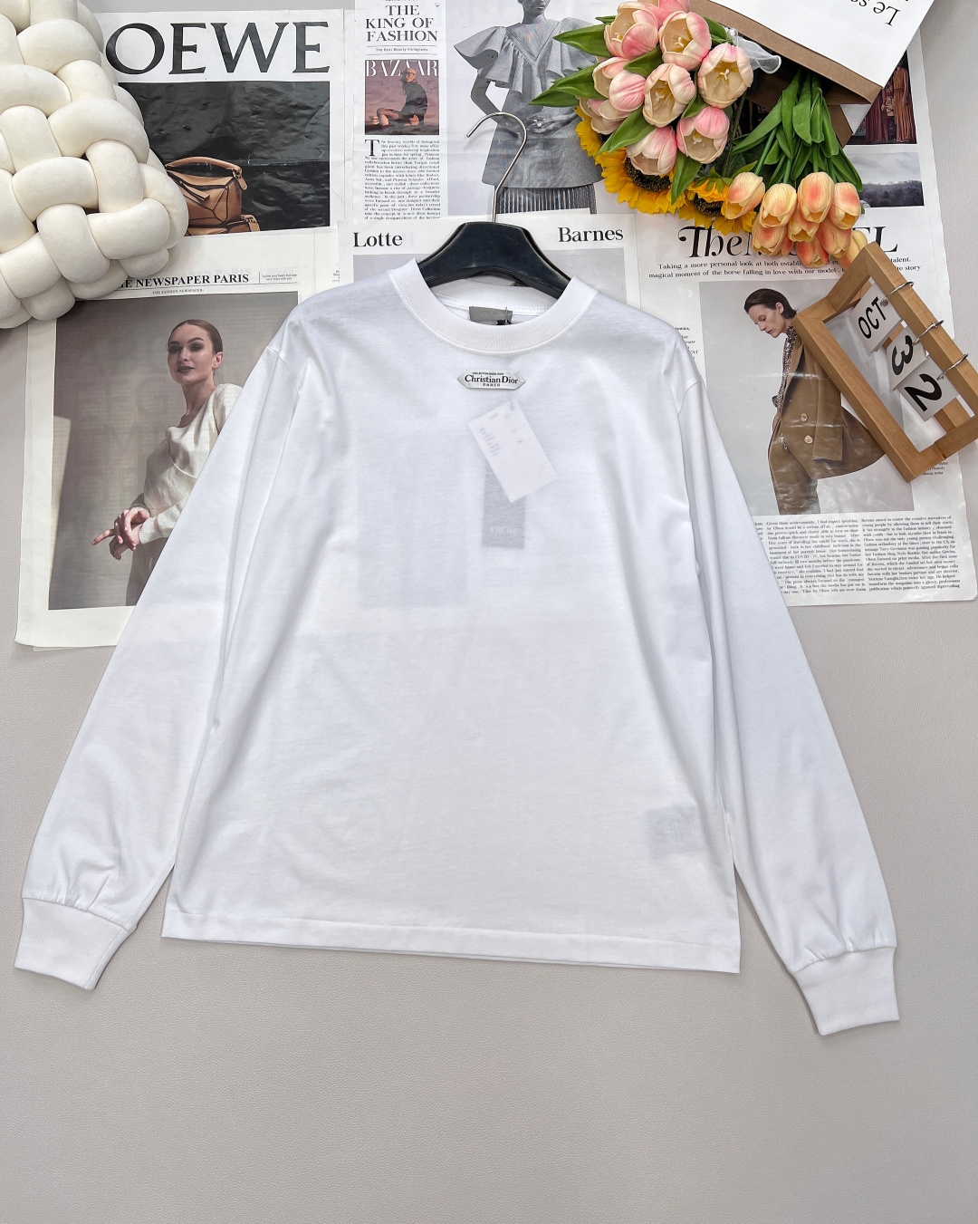 NO:478086,DIOR's new small-label round neck long-sleeved T-shirt, using 24S special-spun tight cotton fabric, 185g; matched with 32S double yarn thread, 300g. The tight spinning strength is higher than that of traditional single yarn, and the single fibers in the tight yarn are arranged tightly, which helps to improve the strength of the yarn. The ends of the fibers are twisted into the yarn, so the yarn is very tight, and the yarn looks smooth and there are fewer hair feathers. The tight spinning yarn has higher strength and fewer hair feathers, which is not easy to cause hair fraying. 'Paris' on the label emphasizes the brand's French ancestry and fashion tradition; it is presented through the jacquard woven label process, reflecting the brand's pursuit of high-end craftsmanship and classic aesthetics. Through the digital jacquard loom  The brand text/pattern is directly woven into the label, with clear texture and no burrs on the edges, which makes it more three-dimensional and durable than ordinary printed labels. High-string cotton material is used to ensure soft touch while maintaining a crispness; classic white-based black characters are interspersed to enhance the texture through the luster of the yarn itself. The neckline is round and curved, suitable for all face shapes and figures; the sleeves are moderately long and just above the elbow, showing a capable and neat image. The slim-fitting tailoring can show the wearer's figure curve while not losing comfort. The neckline, cuffs, hem and other parts are sewn with fine double needle thread. Three standards are complete, large-scale size xssml woven, dior, tees, t-shirt, alexander wang19860909DIOR新款小标签圆领长袖T恤,采用24S特纺紧密棉面料,185g；搭配32S双纱螺纹,300g.紧密纺强力比传统单纱高,紧密纱中的单纤维排列紧密,有助于提高纱线的强力.纤维的端头均捻入纱线内,因此成纱非常紧密,纱线外观光洁毛羽少.紧密纺纱线强力较高毛羽较少,不易产生磨毛的现象. 标签上的“Paris”强调品牌的法式血统与时装传统；通过提花织唛工艺呈现,体现了品牌对高级工艺与经典美学的追求.通过数码提花织机 将品牌文字/图案直接织入标签,纹理清晰、边缘无毛刺,对比普通印刷标签更显立体感与耐久性.采用高支棉材质,确保柔软触感的同时保持挺括；经典白底黑字穿插,通过纱线本身的光泽提升质感. 领口呈现圆润的弧形,适合各种脸型和身材；袖长适中刚好结束在肘部上方,展现出干练利落的形象.采用修身剪裁,能够展现出穿着者的身材曲线,同时不失舒适感.领口、袖口、下摆等部分都有精细双针走线的缝制.三标齐全,大货出 尺码xssml 编,,dior,tees，t-shirt,alexander wang,Women's clothing