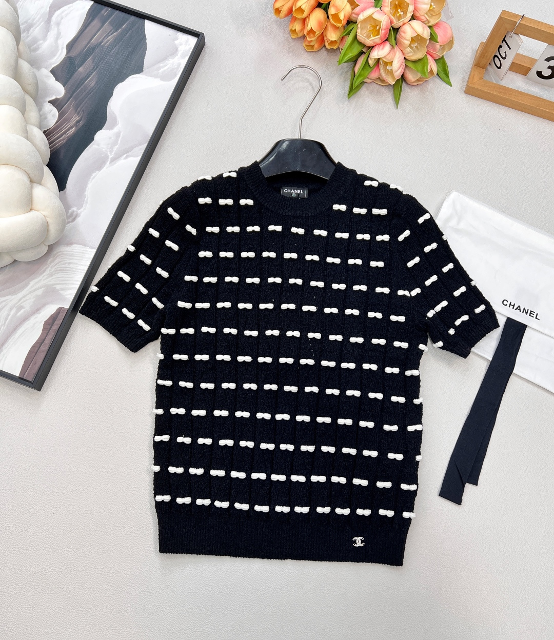 NO:562115,Chanel2025 new bow knitted short-sleeve, custom YB wool yarn weaving, high-end and comfortable texture, pullover knitted short-sleeved cut, contrasting black and white knitting threads are interspersed horizontally throughout the body, visually creating a staggered bow effect, and the hem is decorated with rhinestones  The letter double C pattern, gorgeous and sparkling, creates a collision, highlights the brand personality, highlights the high-end sense of the outfit, allows simple styles to be worn with exquisite personality, and the outfit shows a relaxed tonality, light luxury and fashionable temperament, can be worn alone or layered, the first choice for autumn and winter fashion wear. Customized fabric accessories  Equipped with exquisite lace-up dust bag, complete with three standards, large shipments, size 19860909Chanel2025新款蝴蝶结针织短袖,定制YB羊毛纱线织造,质感高级舒适,套头针织短袖剪裁,通体横向穿插对比色黑白织线,视觉打造蝴蝶结交错效果,下摆装点水钻字母双C图案,华丽闪耀形成碰撞,彰显品牌个性,凸显穿搭高级感,让简单款式穿出个性精致,穿搭尽显松弛调性,轻奢时髦气质,单穿叠穿均可,秋冬时尚穿搭首选.定制面辅料 配有精致系带防尘袋 ,三标齐全,大货出 尺码sml 编码H,,chanel,T-shirt,alexander wang,Women's clothing