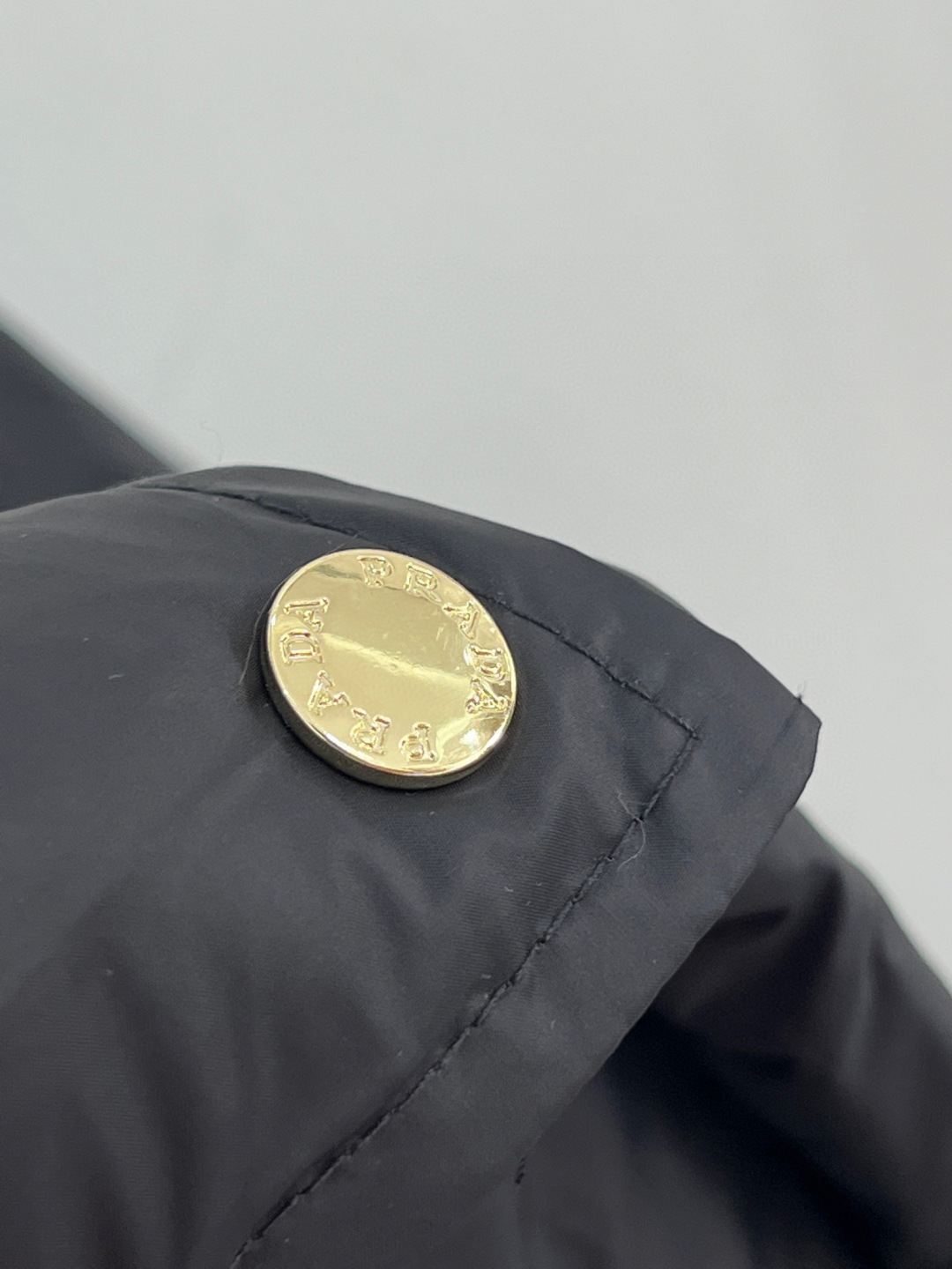 🆕PRAD25FW秋冬三角标连帽羽绒服外套，抽绳末端的金属扣为品牌定制款，质感细腻且经久耐用。门襟选用双