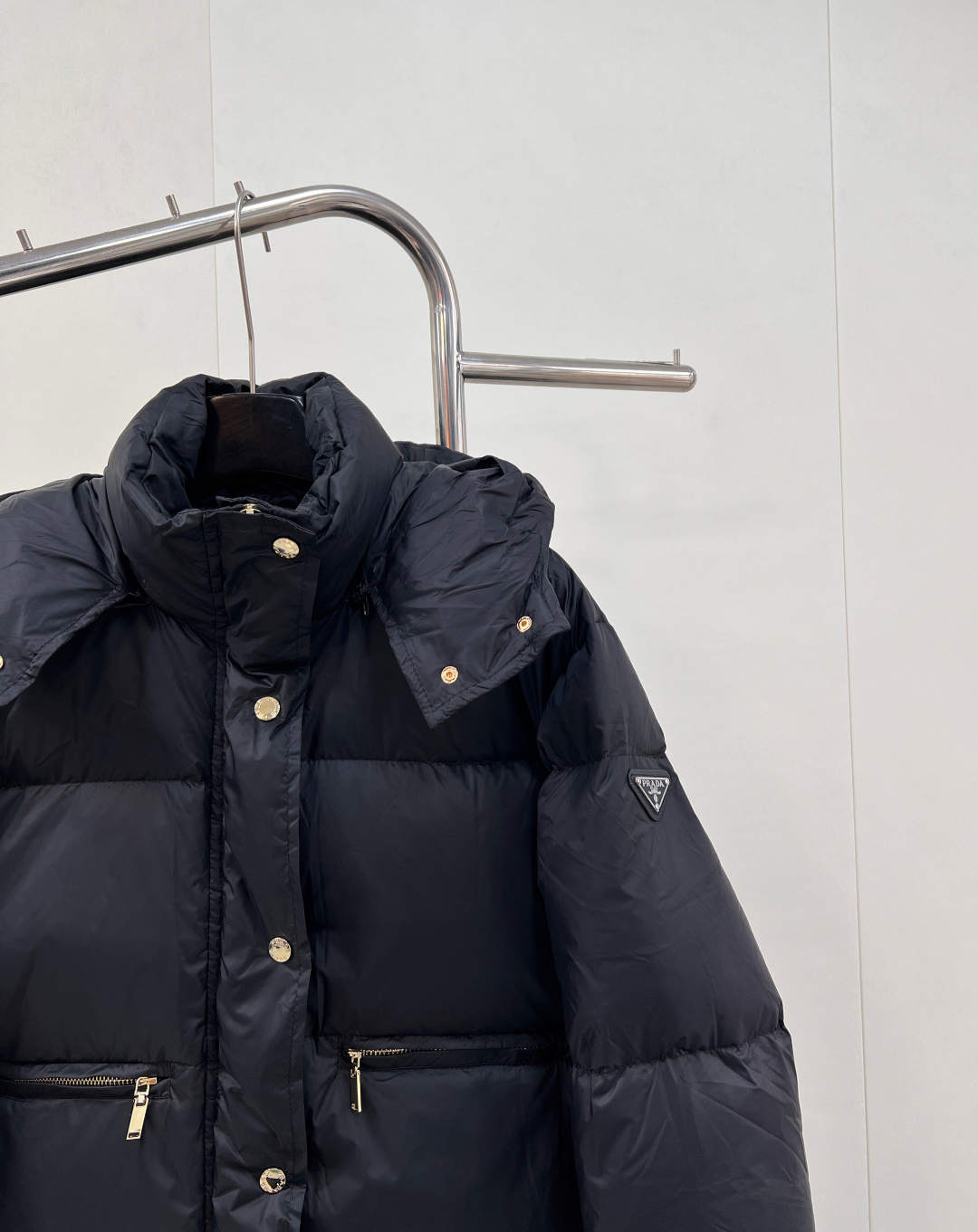 🆕PRAD25FW秋冬三角标连帽羽绒服外套，抽绳末端的金属扣为品牌定制款，质感细腻且经久耐用。门襟选用双