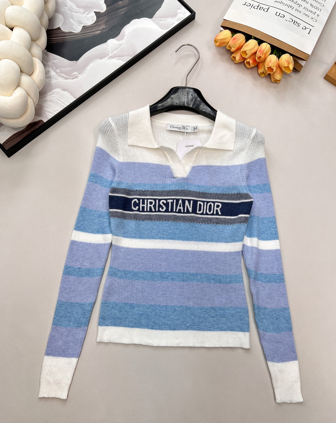 NO:587523,DIOR's new letter crochet striped lapel knitted long-sleeved top; an elegant collision of classic and vitality  The exquisite lapel design instantly outlines the French elegant retro silhouette. The detailed treatment of the V-shaped neckline not only modifies the neck line, but also injects a touch of spontaneity into the overall shape. The splicing of multi-color stripes is the visual focus, and the pink model will  The soft pink is intertwined with deep navy blue and pure white, which is as brilliant as spring flowers; the blue series uses different saturation blues with white and navy blue, like a dialogue between the clear sky and the ocean. Each color combination is highly recognizable and easily brightens up the look.  The most brand-recognizable item is the crocheted 'CHRISTIAN DIOR' letters on the chest. It is presented with exquisite craftsmanship and is full of three-dimensionality. It is a low-key declaration of high-end fashion identity. The knitted fabric is soft and skin-friendly, and the long-sleeved design is suitable for multi-season wear. Whether worn alone to highlight your personality or layered to create layers, it can perfectly control various style scenes, from urban commuting to casual dating, allowing you to always exude Dior-style modern elegance. Complete three standards, large quantities available. Size sml  coding,,dior,dior,alexander wang19860909DIOR新款字母钩花条纹翻领针织长袖上衣；经典与活力的优雅碰撞 精致翻领设计开篇,瞬间勾勒出法式优雅的复古轮廓,V型领口的细节处理,既修饰颈部线条,又为整体造型注入一丝随性.多色条纹的拼接是视觉焦点所在,粉色系款将柔美的粉与深邃的藏蓝、纯净的白交织,如春日繁花般烂漫；蓝色系款则以不同饱和度的蓝搭配白与藏蓝,似晴空与海洋的对话,每一种配色都极具辨识度,轻松点亮造型. 最具品牌辨识度的当属胸前**“CHRISTIAN DIOR”字母钩花**,以精湛工艺呈现,立体感十足,是高级时装身份的低调宣言.针织面料柔软亲肤,长袖设计适配多季穿搭,无论是单穿凸显个性,还是内搭营造层次,都能完美驾驭各种风格场景,从都市通勤到休闲约会,让你时刻散发着迪奥式的摩登优雅.三标齐全,大货出 尺码sml 编码,,dior,dior,alexander wang,Women's clothing