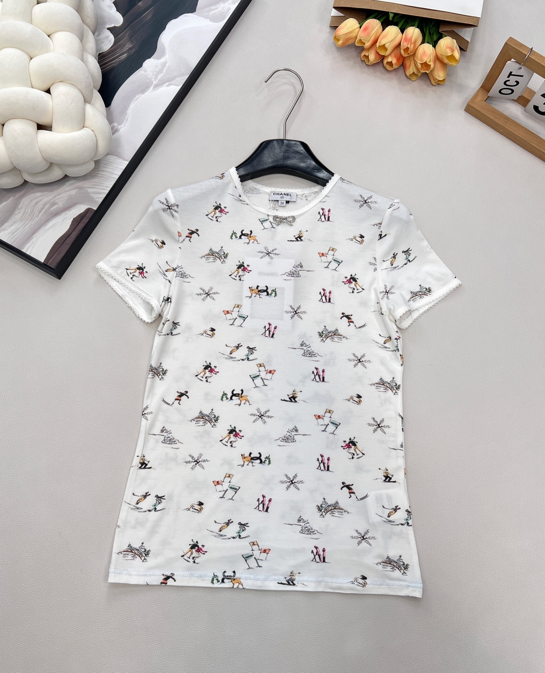 NO:588822,Chanel2025 new round neck printed T-shirt, 25coco ski series #customized YB silk cotton material, comfortable texture, full of elasticity, slim round neck short sleeves, wavy lace binding on the chest, rhinestone bow logo in the center, ski snowflakes and other winter resort elements printed all over the body, incorporating double C logo printing, highlighting the brand style, full elastic fit, visual narrowing and elongation, slim and slim, and stylish when worn alone or worn inside. Customized surface accessories  , complete three standards, large shipments, size sml code H, chanel, T-shirt, tees, t-shirt, alexander wang19860909Chanel2025新品圆领印花T恤,25coco滑雪系列#定制YB丝绵材质,质感舒适,弹力十足,修身圆领短袖裁剪,胸口波浪花边包边,居中位置点缀水钻蝴蝶结徽标,通体满印滑雪雪花等冬日雪场元素,融入双C徽标印花,凸显品牌格调,弹性贴身感十足,视觉收窄拉长,修身显瘦,单穿内搭都出彩时髦.定制面辅料 ,三标齐全,大货出 尺码sml 编码H,,chanel,T-shirt,tees，t-shirt,alexander wang,Women's clothing