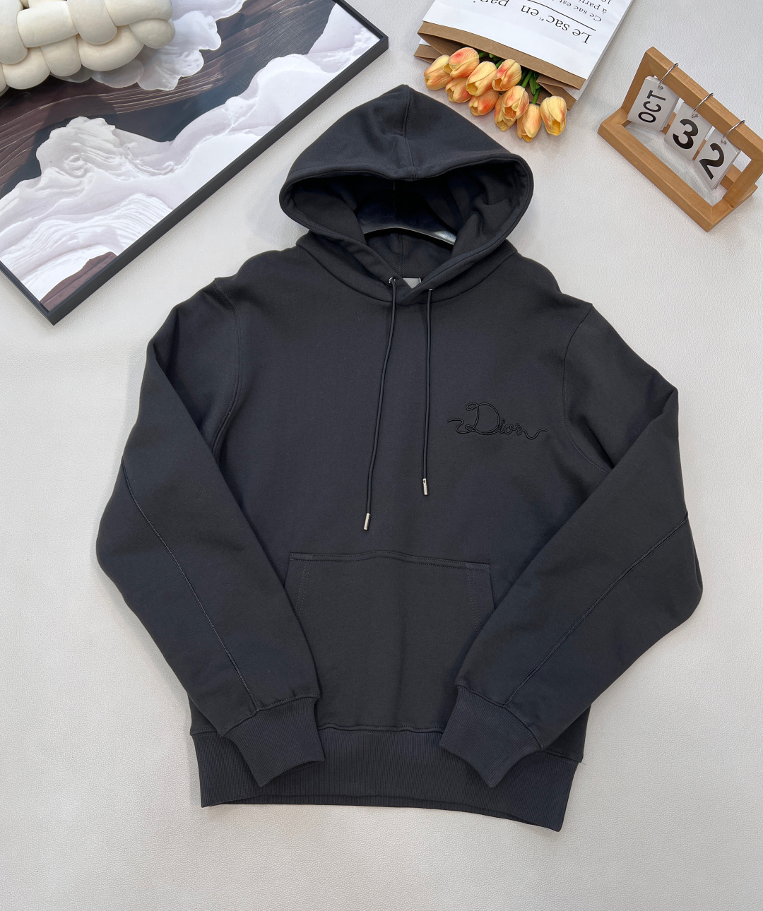 NO:591061,DIOR's new woven satin badge hooded sweatshirt, originally purchased for 16,000; the pure cotton texture fabric is made of terry velvet fabric with a 26-count double yarn base yarn, and the weight is 380g/㎡; it is matched with 21-count 2x2 rib, and the composition is 95 cotton and 5 spandex; the weight is 380g/㎡. The 26-count double yarn is used as the surface yarn, and the yarn is thinner, ensuring the delicate and smooth appearance of the fabric and good color fastness; while the 10-count bottom yarn is used as the terry yarn, the yarn is thicker, and loose loops are formed during weaving. A layer of rich, dense and soft fluff. The high weight gives the sweatshirt a heavy drape and crisp texture, making it less prone to wrinkles and stronger styling capabilities. The pure cotton material ensures excellent breathability, moisture absorption and skin-friendly feel, and the final white color appears pure and rich in texture. Ribbon letter embroidery process, the ribbon itself has a silky luster and smooth touch, which is in sharp and high-end contrast with the matte plush feel of the sweater's suede surface. The embroidery decoration in the form of a ribbon is fixed on the fabric through special processing. The texture brought by this process is usually different from the woven texture and slight luster of the main knitted fabric. It forms an exquisite and accessible visual and tactile focus on the matte dark gray base, which enhances the craftsmanship design and uniqueness of the item. The classic drawstring hoodie is embellished with an engraved bell, and the hood is equipped with engraved hardware accessories; the cuff threads are the same color as the hood. Restore the original design H silhouette, with kangaroo pockets and open-stitch pockets; the sleeve length is longer than usual for more effect, highlighting the casual sexiness of the upper body. Complete with three labels, the same style for men and women! Big shipment, size xssml code, dior, hoodie, sweatshirts, hats, alexander wang19860909DIOR新款织缎徽章连帽卫衣,原16000购买；纯棉质感面料采用26支双纱支底纱的毛圈绒面料,克重380g/㎡；搭配采用21支 2x2 罗纹,成分為95棉与5氨纶；克重380g/㎡. 26支双纱作为表面纱线,纱线更细,确保了面料外观的细腻平整与良好的色牢度；而10支底纱作为毛圈纱,纱线更粗,在织造时形成松散的线圈,经后期统一的起绒或刷绒处理后,在面料内侧形成一层丰厚、浓密且柔软的绒毛.的高克重赋予了卫衣重磅的垂坠感和挺括的骨感,使其不易褶皱,造型能力更强.纯棉的材质保证了极佳的透气性、吸湿性和亲肤感,最终的白色呈现纯净且富有质感. 缎带字母刺绣工艺,缎带本身具有丝质的光泽与顺滑触感,与卫衣起绒面的哑光毛绒感形成鲜明而高级的对比.缎带形式的刺绣装饰,通过工艺特殊处理,使织带固定在面料上.这种工艺带来的质感通常是不同于主体针织面料的梭织质感与轻微光泽,在哑光的深灰色底上形成一个精致而触手可及的视觉与触觉焦点,提升了单品的工艺设计和独特性. 经典抽绳帽衫刻字吊钟点缀,帽口设有刻字五金配件；袖口螺纹与帽位同色同缸.还原版型设计H廓形,配合袋鼠袋明线口袋；袖长比常规偏长一些更有效果,突出上身的随性感.三标齐全,男女同款！大货出 尺码xssml 编码,,dior,hoodie,sweatshirts,hats,alexander wang,Women's clothing