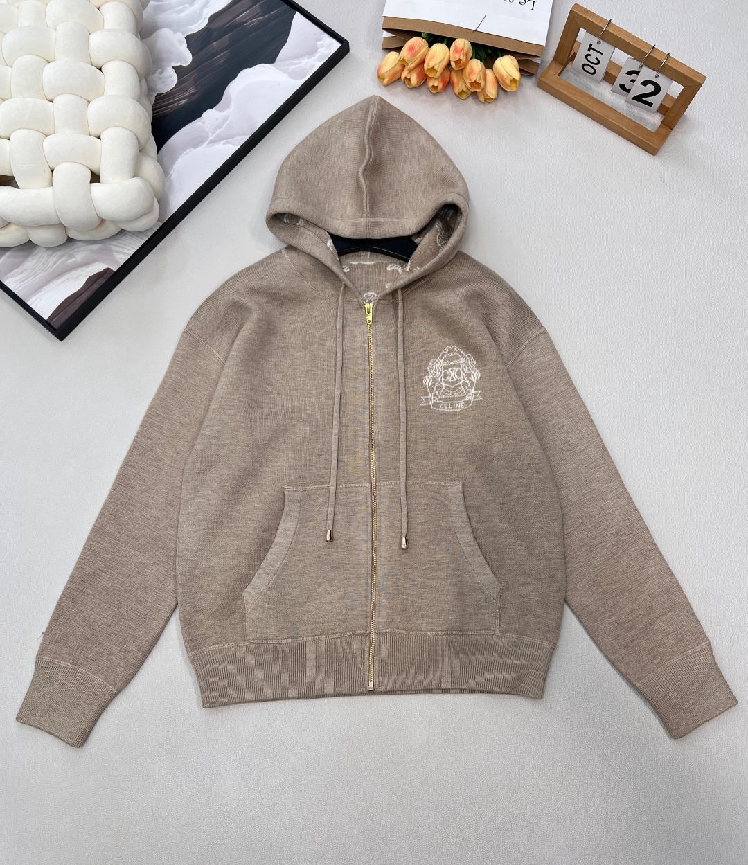 NO:607068,CELINE's new letter logo crochet hooded knitted cardigan is a two-way street between laziness and high-end. It has a gentle beige texture and brings a relaxed atmosphere as soon as you put it on. The hooded design is suitable for a variety of styles. When you are casual, you can pull up the hood and feel casual. When you are commuting, wear it open and look smart and capable.  The golden zipper is smooth and easy to pull, and the large pockets on both sides are practical and fashionable. Put your hands in and instantly unlock the lazy posture. The letter logo crochet on the chest is exquisite and delicate, low-key highlighting the brand style, allowing you to show your high-end taste in every detail.  Wool blended fabric is soft and skin-friendly, with both warmth and breathability. It is suitable for wearing alone in spring and autumn or as an inner layer in winter. Whether it is worn with jeans for a casual and cool style, or with a skirt for an elegant and intellectual style, it can be held perfectly, injecting a unique French sense of luxury into your look, and easily becoming the focus of both comfort and fashion among the crowd. Complete with three standards, large quantities are shipped. Sizes sml code,,celine,skirts,jeans,hats,alexander wang19860909CELINE新款字母徽标钩花连帽针织开衫,慵懒与高级的双向奔赴,浅驼色的温柔质感,一穿上就自带松弛氛围感.连帽设计适配多种风格,休闲时拉上帽子随性自在,通勤时敞开穿又显利落干练. 金色拉链顺滑好拉,两侧大口袋实用又时髦,手插进去瞬间解锁慵懒姿态.胸前字母徽标钩花精致细腻,低调彰显品牌格调,让你在细节处尽显高级品味. 羊毛混纺面料柔软亲肤,兼具保暖性与透气性,春秋单穿、冬季内搭都很合适.无论是搭配牛仔裤走随性潮酷风,还是搭配半裙走优雅知性风,它都能完美hold住,为你的造型注入独特的法式高级感,轻松成为人群中兼具舒适与时尚的焦点.三标齐全,大货出 尺码sml 编码,,celine,skirts,jeans,hats,alexander wang,Women's clothing