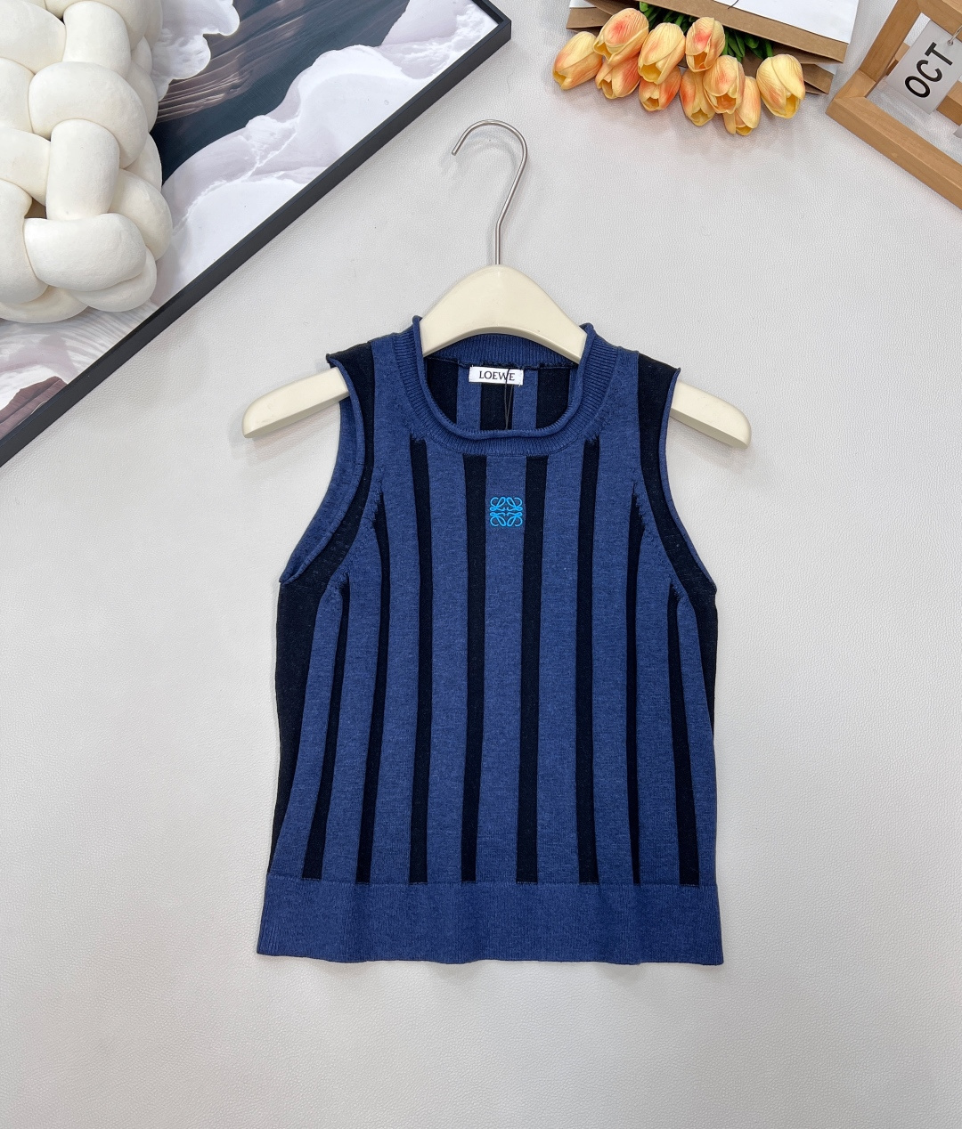 NO:607046,Loewe 2025 new women's sleeveless knitted vest, an elegant statement in minimalist lines, minimalist design meets high-end texture, Ll uses wide rib technology to outline a neat silhouette, and the short cut just optimizes body proportions. The sleeveless design releases casual tension in spring and summer, and can also be the finishing touch of layering in autumn and winter. Blue and black vertical stripes interweave classic rhythm, and the exquisite embroidered letters on the chest are a low-key expression of the brand's genes, and every stitch is hidden  Loewe's obsessive pursuit of details. It is a smart combination with suit pants when commuting, a casual collision with denim items when going out on the street, and an elegant interpretation of 'less is more' in the light luxury style - a vest, N styles, allowing you to accurately capture the Loewe-style sense of luxury in every outfit. Complete with three standards, large quantities available. Size sml code L,, loewe, business suit, alexander wang19860909Loewe 2025 新款女装无袖针织背心,极简线条里的优雅宣言,极简设计邂逅高级质感,Ll以宽罗纹工艺勾勒利落版型,短款剪裁恰到好处地优化身材比例,无袖设计在春夏季节释放随性张力,亦能在秋冬作为叠搭层次的点睛之笔.蓝黑竖条纹交织出经典韵律,胸前精致刺绣字母是品牌基因的低调彰显,每一针都藏着 Loewe 对细节的偏执追求. 它是通勤时与西装裤的干练组合,是出街时和牛仔单品的随性碰撞,更是轻奢风格里“少即是多”的优雅诠释——一件背心,N 种风格,让你在每一次穿搭中,都能精准拿捏 Loewe 式的高级感.三标齐全,大货出 尺码sml 编码L,,loewe,business suit,alexander wang,Women's clothing