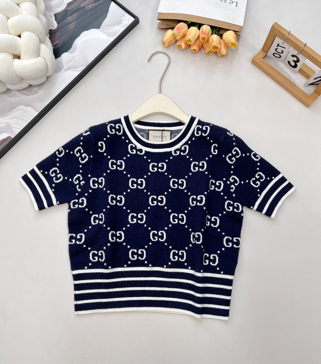 NO:797668,GUCCI's new GG rhombus knitted top, a classic collision of blue and white, interpreting modern retro style!  When the classic blue and white meets GUCCI's iconic GG rhombus, a fashionable knitted item for spring and summer is born. The custom-dyed blue and white yarn is carefully woven, injecting the brand's century-old elegant gene into every inch of the texture. The GG rhombus is laid out all over, which is a high-profile statement of recognition and a modern interpretation of retro aesthetics.  The neat lapels and short-sleeve design outline a refreshing silhouette; the short cut cleverly raises the waistline and easily creates the golden ratio. Whether paired with high-waisted jeans to show a casual trend, or paired with a skirt to show an elegant style, it can become the focus of the style with a 'foreign and fashionable' attitude, allowing you to walk the line between classic and trendy in spring and summer wear, and walk out your own luxurious and elegant pace. Size sml  coding,,gucci,skirts,T-shirt,gold,19860909GUCCI新款GG菱格针织上衣,蓝白经典碰撞,演绎摩登复古风情！当经典蓝白邂逅GUCCI标志性GG菱格,一件属于春夏的时髦针织单品就此诞生.定染蓝白纱线精心编织,将品牌百年奢雅基因注入每一寸肌理,GG菱格满幅铺陈,是辨识度的高调宣言,更是复古美学的摩登演绎. 利落翻领搭配短袖设计,勾勒清爽轮廓；短款剪裁巧妙提升腰线,轻松打造黄金比例.无论是搭配高腰牛仔彰显随性潮范,还是衬以半身裙流露优雅格调,它都能以“洋气时髦”的姿态,成为造型的吸睛焦点,让你在春夏穿搭中,于经典与潮流的边界,走出独属于自己的奢雅步调. 尺码sml 编码,,gucci,skirts,T-shirt,gold,,Women's clothing