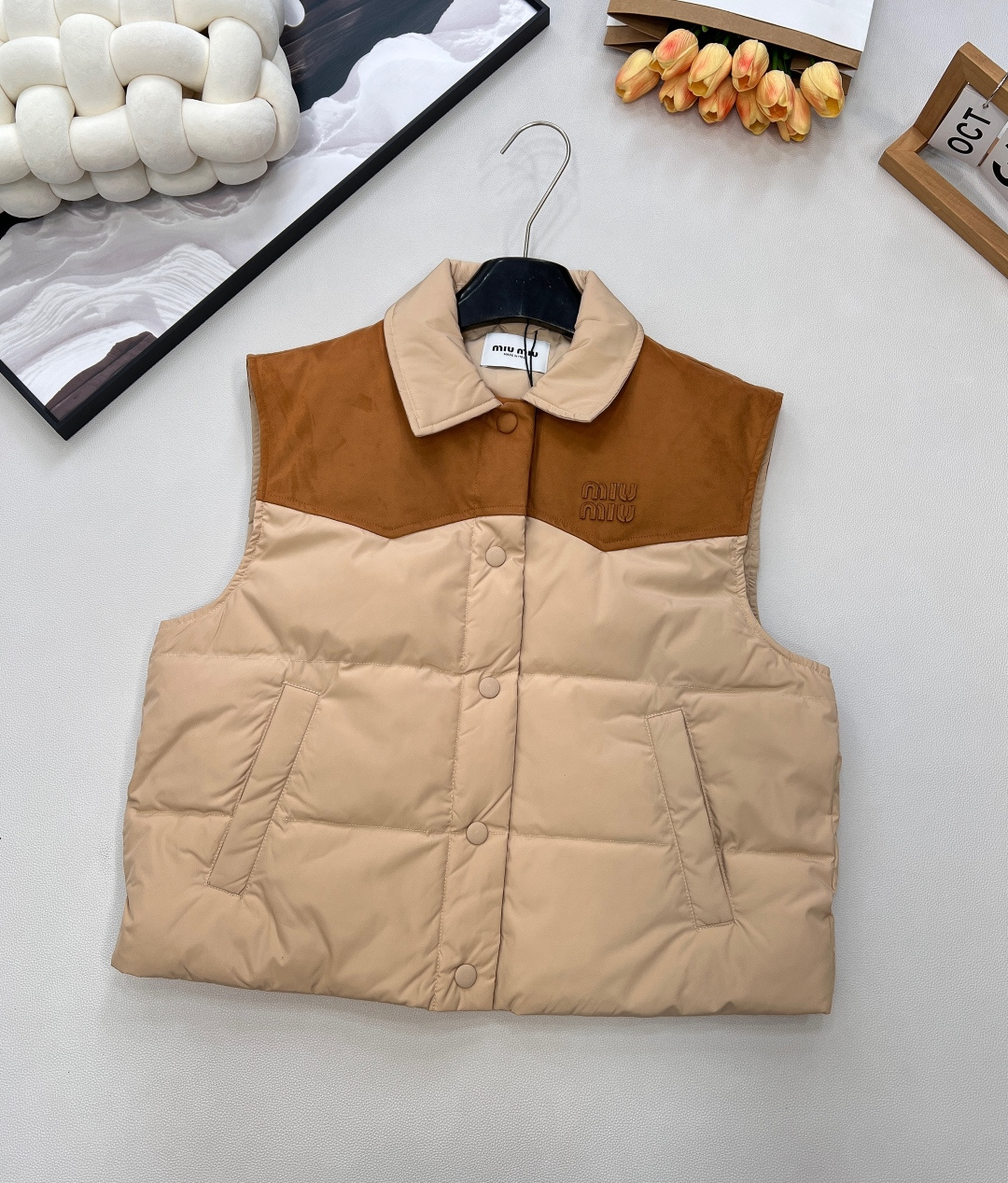 NO:607999,Comes with dust bag MiuMiu25FW new autumn and winter leather logo lapel stitching contrasting down vest丨Exclusive high-end version!  The core design is leather splicing + letter logo. The collar/shoulder area is made of caramel brown suede-like leather, which collides with the main milk tea apricot nylon fabric. It comes with a retro lazy filter; 90 white goose down filling  , with high fluffiness but no weight-bearing feeling, taking into account the cold weather in autumn and winter and the flexibility of daily wear. The lapel version is suitable for layering, the single-row button opening and closing is easy to put on and take off, and the quilted and down-filled technology keeps you warm without looking bulky; the two colors are outstanding  Size sml code,,miumiu,down jacket,chamois leather,alexander wang19860909配防尘袋 MiuMiu25FW秋冬新款皮革徽标翻领拼接撞色羽绒马甲丨独家高版出品！以皮革拼接+字母徽标为核心设计,领口/肩背区域采用焦糖棕麂皮质感皮革,与主体奶茶杏尼龙面料碰撞,自带复古慵懒滤镜；90白鹅绒填充,蓬松度高却无负重感,兼顾秋冬御寒与日常穿搭的灵动感.翻领版型适配叠穿,单排纽扣开合方便穿脱,绗缝充绒工艺既保暖又不显臃肿；两色出 尺码sml 编码,,miumiu,down jacket,chamois leather,alexander wang,Women's clothing