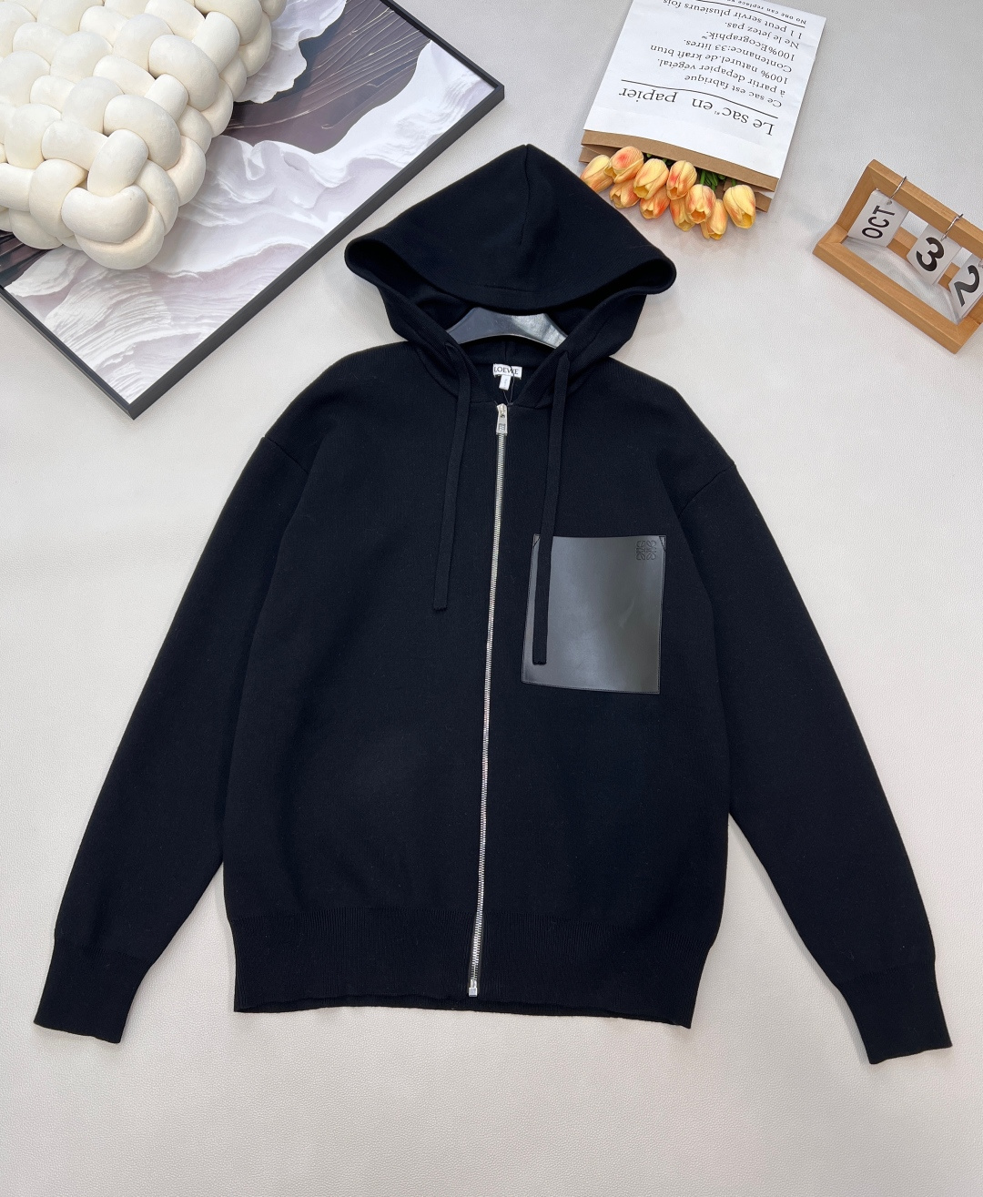 NO:610468,LOEWE's new small label leather patch pocket sweater cardigan, blended wool weaving, leather chest patch pockets, chest pockets with Anagram embossing, front zipper closure, specific color blended wool, using 32S woven pieces blended with wool and cotton yarn. The blend combines the top properties of both fibers. Wool provides excellent warmth, natural elasticity and excellent drape, while cotton yarn ensures skin-friendly comfort, breathability and practicality for daily wear.  The 32-count yarn is a medium-to-high count, which ensures the fineness and tightness of the fabric and avoids the roughness of low-count yarns. The double-sided structure makes the front and back of the fabric have the same texture or can be used as the front, achieving double the practicality and high-end touch.  Embossed Leather Chest Patch Double-sided leather chest patch bag is a heavy-duty detail processing. The material of the double-sided leather pocket is specially treated high-quality leather that can be used on both sides. Its edges are hemmed or hemmed and stitched to present a complete and exquisite outline. The Anagram embossing on the pocket is a permanent brand logo recessed pattern formed on the leather surface through a high-temperature and high-pressure mold embossing process. Zipper closure hooded structure  The ribbed cuffs and hem are made of highly elastic ribbed knit fabric, which tightens the opening to prevent cold wind from pouring in, and contrasts with the loose silhouette of the body to clean the overall lines. The front zipper closure provides greater convenience and ventilation adjustment capabilities, making its style more biased towards sports and outdoor jackets. The regular fit and standard length ensure a well-fitting and easy-to-match silhouette. Double-sided stitching  Processing, all seams adopt advanced sewing technology such as flat lock seams. Its function is to perfectly hide the seam inside the clothing or make it fit flatly, thereby improving the comfort of wearing underwear. The same style for men and women, complete with three standards!  Big shipment, size xssml code L,,loewe,jackets & coats,sweaters,hats,alexander wang19860909LOEWE新款小标皮革贴袋毛衣开衫,混纺毛料织造、皮革胸前贴袋、胸前口袋有 Anagram 压纹、正面拉链开合、对色特定混纺毛料,采用羊毛与棉纱混纺的32S织片,混纺结合了两种纤维的顶级特性羊毛提供卓越的保暖性、天然的弹性和优异的悬垂感,而棉纱则保证了亲肤的舒适度、透气性和日常穿着的实用性. 32支的纱线属于中高支数,确保了织片的细腻度和紧实度,避免了低支纱的粗糙感.双面结构使面料正反面质感一致或均可用作正面,实现了双倍的实用性和高级的触感. 压纹皮革胸前贴袋双面皮革胸前贴袋是一项重工细节处理.双面皮革口袋的材质是经过特殊处理的、正反两面皆可使用的优质皮革,其边缘通过包边或折边缝合处理,呈现出完整精致的轮廓.口袋上的Anagram压纹是通过高温高压的模具压印工艺在皮革表面形成永久性的品牌标识凹陷图案. 拉链开合连帽结构 罗纹袖口和下摆由高弹性的罗纹针织面料制成,其作用是收紧开口,防止冷风灌入,并与衣身的宽松廓形形成对比,利落整体线条. 正面拉链开合提供了更大的便利性和通风调节能力,使其风格更偏向于运动和外穿夹克.常规版型与标准长度确保了合身且易于搭配的轮廓.双面缝线 处理,所有接缝都采用了扁平锁缝等高级缝制技术,其作用在于将缝份完美隐藏于衣物内部或使其平整贴合,从而提升内衣穿着时的舒适度.男女同款,三标齐全！大货出 尺码xssml 编码L,,loewe,jackets & coats,sweaters,hats,alexander wang,Women's clothing