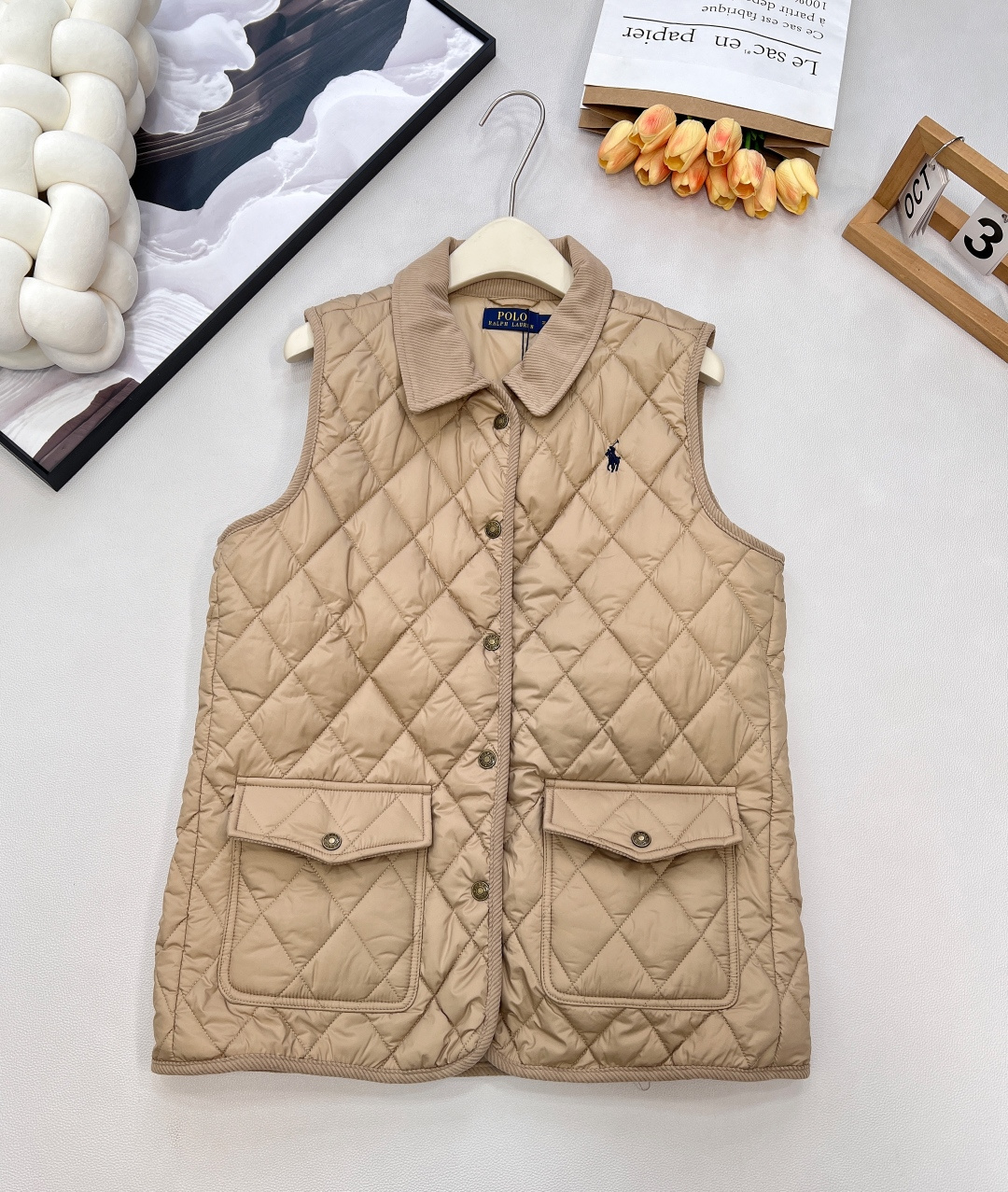 NO:624158,Ralph Lauren's new corduroy-trimmed quilted vest is a classic American relaxed early-autumn 'atmosphere artifact' with retro details and environmentally friendly textures. It is a versatile ace in the layering season. 'Retro contrasting colors, texture is in the details' - Corduroy-trimmed wide-angle lapels, plackets, armholes, pocket edges and hems are all spliced with corduroy. It has a warm-toned texture with a retro filter, making it easy to adapt to layering scenes such as jeans and shirts; -  The iconic logo is embroidered with a classic pony logo on the left side of the chest, showing brand recognition in a low-key manner; - Practical design snap-button placket + double snap-button patch pockets at the waist, a sleeveless silhouette that is neat and not bulky, and side panels to increase room for movement. Lightly padded diamond-shaped quilting is both warm and lightweight without weighing down the body; the entire piece is made of recycled polyester fiber (fabric + filling), which retains a crisp texture while practicing the concept of sustainable fashion.  Three soft colors are available (white/khaki/navy), suitable for commuting, leisure and other various occasions. It is a 'simple but not simple' texture item in the early autumn wardrobe. Complete with three standards, large quantities are shipped. Size sml code R,, loro piana, shirts, alexander wang19860909Ralph Lauren 新款灯芯绒饰边绗缝马甲,经典美式松弛感的早秋“氛围感神器”,复古细节碰撞环保质感,是叠穿季的百搭王牌. 「复古撞色,细节见质感」 - 灯芯绒饰边宽角翻领、门襟、袖孔、口袋边缘与下摆均以灯芯绒拼接,自带复古滤镜的暖调质感,轻松适配牛仔、衬衫等叠穿场景； - 标志性标识胸前左侧绣有经典小马标,低调中透出品牌辨识度； - 实用设计按扣式门襟+腰部双按扣贴袋,无袖廓形利落不臃肿,侧边镶片增加活动余量.轻度填充的菱形绗缝,兼顾保暖与轻盈不压身；全件采用再生聚酯纤维（面料+填充物）,在保留挺括质感的同时,践行可持续时尚理念. 三色可选的柔和色系（白/卡其/藏青）,适配通勤、休闲等多元场合,是早秋衣橱里“简约不简单”的质感单品.三标齐全,大货出 尺码sml 编码R,,loro piana,shirts,alexander wang,Women's clothing