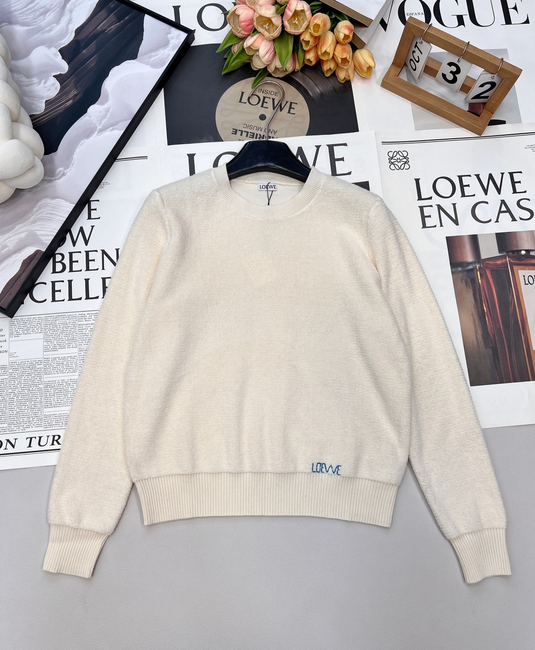 NO:655131,Loewe's new letter-embroidered sweater brings 'elegant relaxation' to the body. The round neck + embroidered logo = the 'universal card' for the autumn and winter wardrobe. The simple and basic style has the most texture - the gentle round neck is suitable for various inner and outer wear. The slightly loose version hides the flesh and stretches, and it is effortless elegance when raising your hands.  The textured knitted fabric on the surface has a delicate luster and feels soft against the skin like a layer of clouds; the mini embroidered logo on the hem is low-key and discreet, delicate and unobtrusive, and makes you look noble at a glance. The two colors have their own atmosphere - the milky white is gentle and can be worn with a skirt to look like a wealthy daughter, and paired with jeans can be a relaxed commute - navy blue is the 'king of slimming' in autumn and winter, and it is high-end when worn with a layered coat or worn alone with boots.  Two colors and three sizes are available in seconds. Whether it is daily commuting or light dating, you will win in quality when you put it on ~ complete three standards, two colors, size sml code, loewe, boots, skirts, jeans, alexander wang19860909Loewe新款字母刺绣针织衫,把“优雅松弛感”穿在身上,圆领+刺绣Logo=秋冬衣橱的“万能牌” 简约基础款最见质感——温柔圆领适配各种内搭外穿,微微宽松的版型藏肉又舒展,抬手间都是不费力的优雅. 表面的肌理针织自带细腻光泽,贴肤软乎乎的像裹了层云朵；下摆的迷你刺绣Logo是低调小心机,精致不张扬,一眼就显贵. 两色各有氛围 - 奶白色温柔挂天菜,搭半裙是富家千金,配牛仔裤是松弛通勤 - 藏青色秋冬里的“显瘦王者”,叠穿大衣/单穿配靴都高级 二色三码现货秒发,不管是日常通勤还是轻约会,套上就赢在质感~三标齐全,两色出 尺码sml 编码,,loewe,boots,skirts,jeans,alexander wang,Women's clothing
