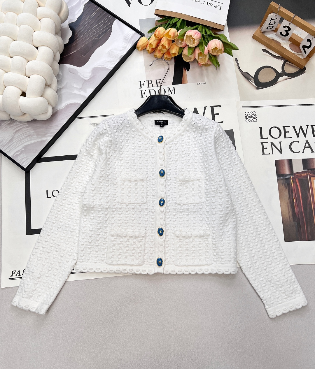 NO:667084,CHANEL's new classic white embossed knitted cardigan is one of the iconic styles of 'Xiao Xiangfeng' - The fabric details are overall three-dimensional embossed knitted texture (similar to the texture of 'seersucker'), plus a double pocket design, with a delicate texture; - The blue and gold contrast buttons on the placket are the highlight, breaking the monotony of pure white, retro and noble; -  Features of the version: short style + round neck + edged lace. It is a gentle and elegant slim fit, suitable for all kinds of light French and commuting wear. The material is wool blended, taking into account both texture and comfort. It is a very versatile basic style in small fragrances. Complete with three standards, large quantities are shipped. Size sml code H,,chanel, 19860909CHANEL新款经典的白色浮雕针织开衫,是“小香风”的标志性款式之一 - 面料细节整体是立体浮雕针织纹理（类似“泡泡纱”质感）,加上双口袋设计,自带精致的肌理感； - 点睛元素门襟的蓝金撞色纽扣是亮点,打破纯白的单调,复古又贵气； - 版型特点短款+圆领+收边蕾丝花边,属于温柔优雅的修身款,适配各种轻法式、通勤穿搭. 材质是羊毛混纺,兼顾质感和舒适度,是小香风里很百搭的基础款.三标齐全,大货出 尺码sml 编码H,,chanel, ,Women's clothing