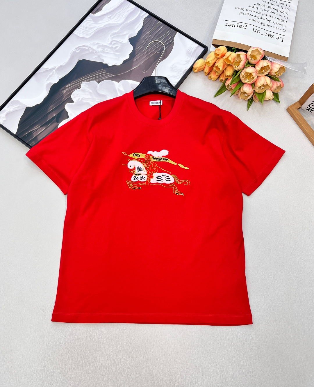 NO:709420,Burbery26SS New Year Limited Equestrian Knight Logo Round Neck Short Sleeve T-Shirt丨Exclusively developed by yb!  High quality production!  The classic round neck cut is matched with a loose silhouette, and soft cotton fabrics are selected to create a comfortable wearing feeling. The embroidered equestrian knight logo on the chest is integrated into the New Year red/pure white two-color design.19860909Burbery26SS新年限定马术骑士徽标圆领短袖T恤丨独家yb开发！高版出品！以经典圆领剪裁搭配宽松廓形,甄选柔软棉质面料打造舒适穿着感.胸前刺绣马术骑士徽标融入新年红/纯净白双色设计,徽标细节采用立体绣艺呈现,新年限定款的红色调更添节日氛围,简约版型适配日常多种穿搭场景,是轻奢休闲与节日仪式感的融合之作.三标齐全,三色出 尺码sml 编码B,,burberry,T-shirt,tees，t-shirt,,Women's clothing