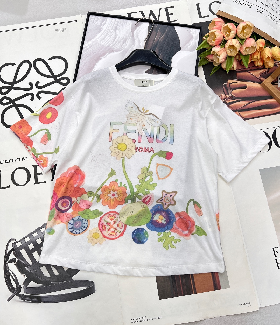 NO:734930,FENDI's new short-sleeved T-shirt with floral print lettering, let's start with this FENDI piece. It is made of pure white as the base, and hand-painted colorful flowers cover the body. The colors are rich and naturally smudged, as if you are wearing a spring garden on your body. The iconic 'FENDI ROMA' letters are integrated into the flowers, and the gradient color echoes the printing. The brand logo and artistic aesthetics are perfectly integrated, making it recognizable at a glance.  It is made of light and breathable cotton fabric with soft drape. The loose cut is suitable for various body shapes and can be easily controlled for daily outings and afternoon tea dates. It has both freshness and vitality and Italian elegance. It is an eye-catching item that lights up the spring and summer wardrobe. It has three standards and is shipped in large quantities. Sizes sml code, fendi, T-shirt, tees, t-shirt,19860909FENDI 新款字母花卉印花短袖T恤,邂逅夏日浪漫,从这件FENDI开始. 以纯净白为底,手绘感的缤纷花卉铺满衣身. 色彩层次丰富且晕染自然,仿佛将春日花园穿在身上. 标志性的“FENDI ROMA”字母融入花朵之间,渐变色彩与印花呼应. 品牌标识与艺术美学完美融合,一眼尽显辨识度. 采用轻盈透气的棉感面料,垂坠柔和. 宽松剪裁适配各种身形,日常出街、约会下午茶都能轻松驾驭. 清新活力与意式优雅兼具,是点亮春夏衣橱的吸睛单品.三标齐全,大货出 尺码sml 编码,,fendi,T-shirt,tees，t-shirt,,Women's clothing