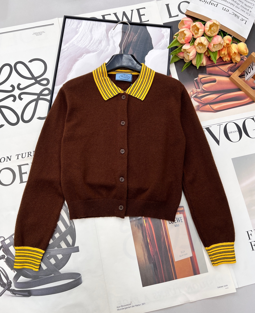 NO:734923,Prada26Ss new early spring contrasting color lapel knitted cardigan丨Exclusive high-end version!  It is made of warm and rich caramel brown wool blended fabric, which feels soft and waxy and dense, and has skin-friendly and warm properties. The collar and cuffs are spliced with yellow and black striped ribs, and the retro college-style design echoes the fashion trends of the season and visually brightens the overall look. The neat short cut is paired with exquisite buttons  The buttoned placket optimizes the proportions of the body while showing a casual elegance. The back is decorated with a triangular logo in a low-key manner, and the details highlight the luxury gene. Whether worn with a suspender skirt to create a sweet and cool style, or paired with jeans to create a relaxed feel, it can be the finishing touch of the style. Complete with three standards, large quantities are available.  size sml code,,prada,skirts,jeans,19860909Prada26Ss早春新款撞色翻领针织开衫丨独家高版出品！以温暖浓郁的焦糖棕羊毛混纺面料为主体,触感软糯绒密,自带亲肤保暖属性.领口与袖口拼接黄黑条纹罗纹,复古学院风设计呼应当季流行趋势,视觉上点亮整体造型.利落短款剪裁搭配精致纽扣门襟,优化身材比例的同时尽显随性优雅.后背低调点缀三角徽标,细节处彰显奢华基因,无论是内搭吊带裙打造甜酷风,还是配牛仔裤营造松弛感,都能成为造型点睛之笔.三标齐全,大货出 尺码sml 编码,,prada,skirts,jeans,,Women's clothing
