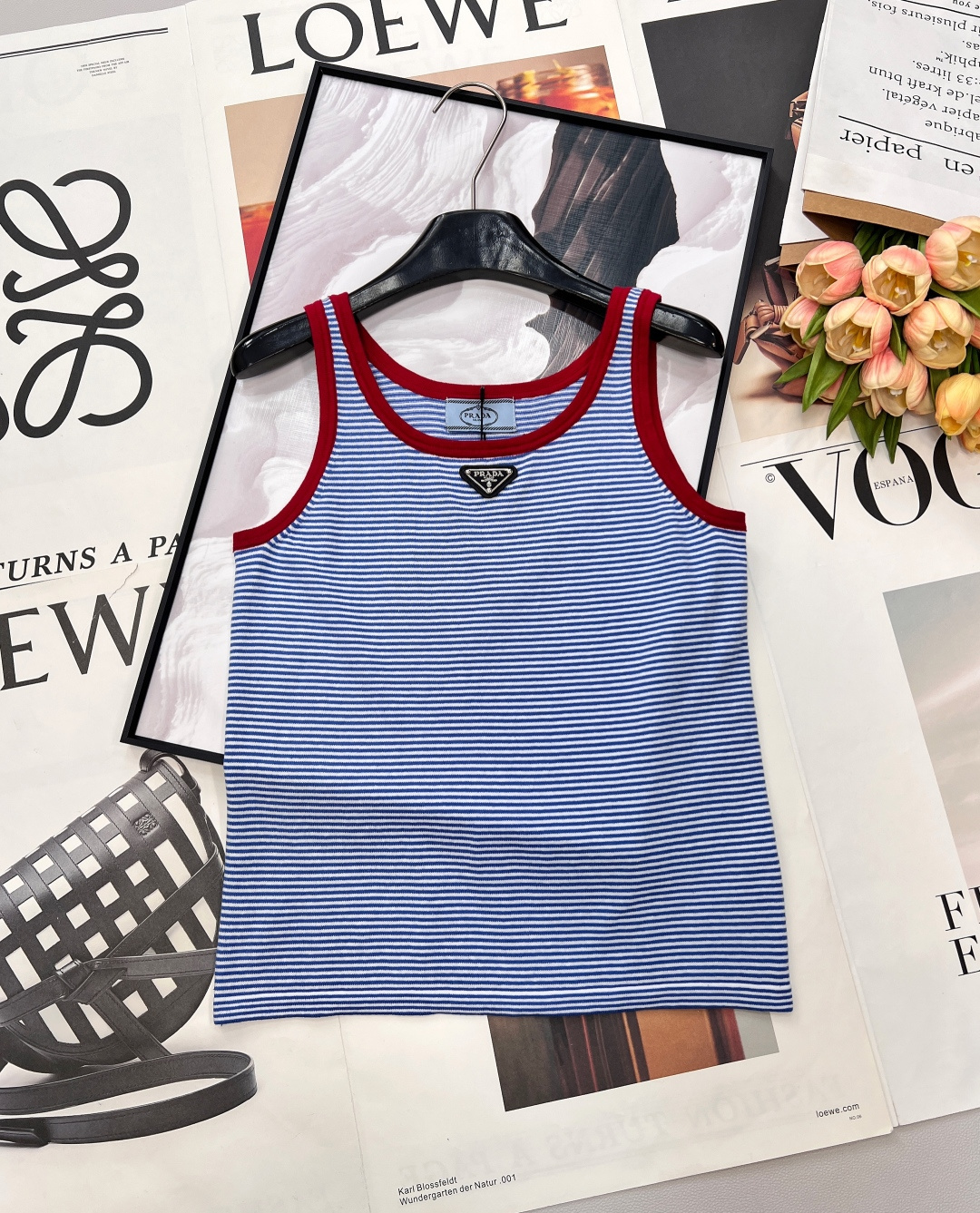 NO:738868,Prada striped knitted vest, red and blue contrasting colors + triangle logo, full of summer retro feeling, playing the role of retro vitality in summer wardrobe. The classic blue and white pinstripes bring a refreshing atmosphere, and the contrasting red rib design on the collar and shoulder straps instantly breaks the monotony and becomes an eye-catching highlight. The iconic triangle metal logo on the chest low-key highlights the brand identity, coexisting with texture and recognition.  .Select soft, waxy and breathable knitted fabrics that are skin-friendly and comfortable with a sense of drape. The loose tailoring is casual and stylish. Wearing it alone is a vigorous and casual style. Layering it with a denim jacket, shirt or knitted cardigan can unlock a retro accent. Whether paired with denim shorts, pleated skirts or wide-leg pants, you can easily capture the summer fashion sense and make every time you go out on the street full of vitality. Complete with three standards, large quantities!  Size sml code P,,prada,skirts,shorts,jackets & coats,shirts,19860909Prada条纹针织背心,红蓝撞色+三角徽标,夏日复古感拉满,夏日衣橱里的复古活力担当.经典蓝白细条纹自带清爽氛围感,领口与肩带的红色罗纹撞色设计,瞬间打破单调,成为吸睛亮点.胸前标志性三角金属徽标,低调彰显品牌身份,质感与辨识度并存.甄选软糯透气的针织面料,亲肤舒适又有垂坠感,宽松剪裁随性有型,单穿是元气休闲风,叠穿牛仔外套、衬衫或针织开衫又能解锁复古腔调.无论是搭配牛仔短裤、百褶裙还是阔腿裤,都能轻松拿捏夏日时尚感,让每一次出街都充满活力.三标齐全,大货出！ 尺码sml 编码P,,prada,skirts,shorts,jackets & coats,shirts,,Women's clothing