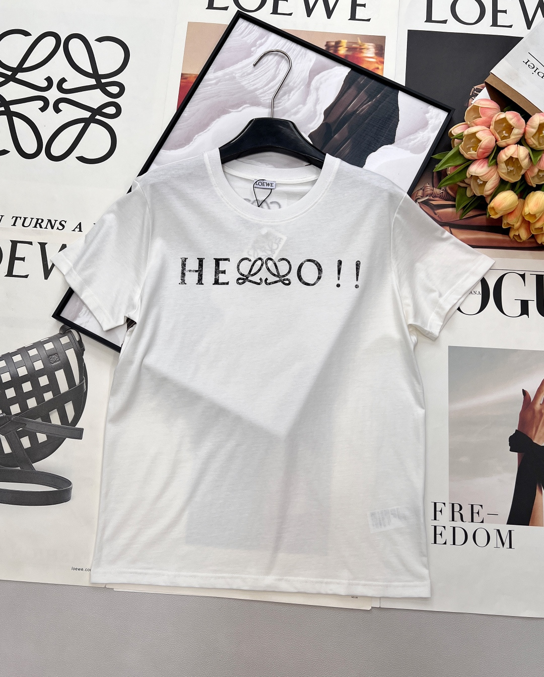 NO:739295,LOEWE's new HELLO letter-printed short-sleeved T-shirt uses the iconic LOEWE double L intertwined pattern and cleverly integrates the word 'HELLO', which is like a relaxed opening statement to break the daily dullness. The high-count cotton fabric is selected, soft and skin-friendly, breathable and not stuffy. Whether worn alone or layered, it can easily create a sense of relaxation. It is available in black and white, suitable for various styles, and is a versatile item that will never go out of style in the wardrobe.  Whether paired with casual trousers, elegant skirts, or layered jackets, you can easily create a high-end daily or urban fashion look. LOEWE classic T-shirt - interpret timeless style with details. Complete with three standards and two colors!  Size sml code,,loewe,loewe,skirts,jackets & coats,T-shirt,tees,t-shirt,19860909LOEWE新款罗意威HELLO字母印花短袖T恤,以标志性的LOEWE双L交织图案,巧妙融入“HELLO”字样,像一句轻松的开场白,打破日常的沉闷.甄选高支棉面料,软糯亲肤,透气不闷,无论是单穿还是叠搭,都能轻松营造松弛感.黑白两色,适配各种风格,是衣橱里永不过时的百搭单品. 无论是搭配休闲裤装、优雅裙装,还是叠穿外套,都能轻松打造高级感日常或都市时髦look.  LOEWE经典款T恤——用细节诠释永恒风格.三标齐全,两色出！ 尺码sml 编码,,loewe,loewe,skirts,jackets & coats,T-shirt,tees，t-shirt,,Women's clothing