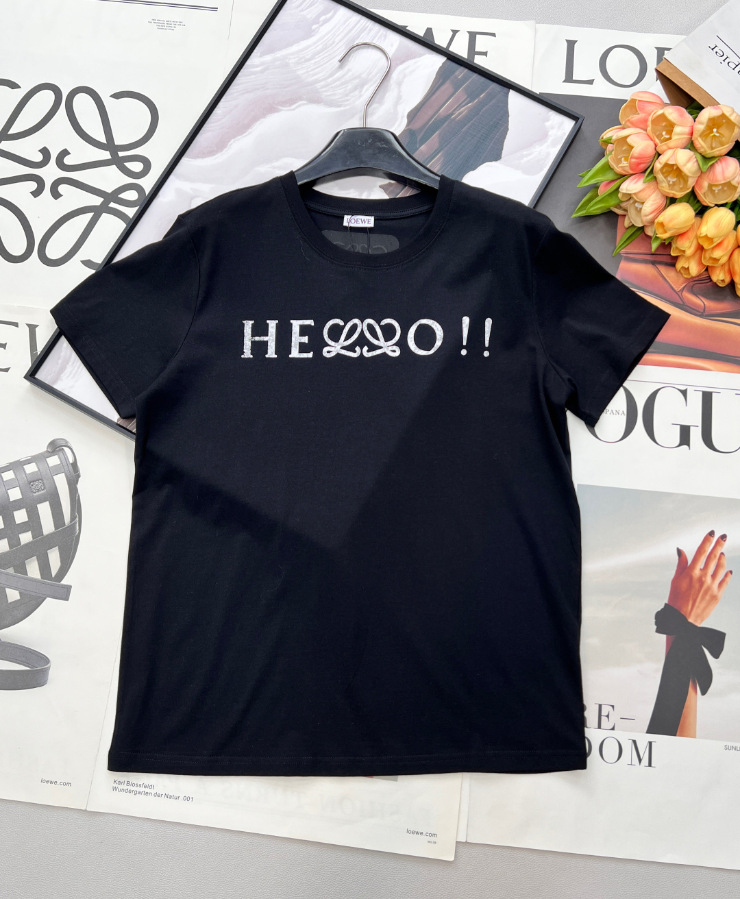 NO:739301,LOEWE's new HELLO letter-printed short-sleeved T-shirt uses the iconic LOEWE double L intertwined pattern and cleverly integrates the word 'HELLO', which is like a relaxed opening statement to break the daily dullness. The high-count cotton fabric is selected, soft and skin-friendly, breathable and not stuffy. Whether worn alone or layered, it can easily create a sense of relaxation. It is available in black and white, suitable for various styles, and is a versatile item that will never go out of style in the wardrobe.  Whether paired with casual trousers, elegant skirts, or layered jackets, you can easily create a high-end daily or urban fashion look. LOEWE classic T-shirt - interpret timeless style with details. Complete with three standards and two colors!  Size sml code L,,loewe,loewe,skirts,jackets & coats,T-shirt,tees,t-shirt,19860909LOEWE新款罗意威HELLO字母印花短袖T恤,以标志性的LOEWE双L交织图案,巧妙融入“HELLO”字样,像一句轻松的开场白,打破日常的沉闷.甄选高支棉面料,软糯亲肤,透气不闷,无论是单穿还是叠搭,都能轻松营造松弛感.黑白两色,适配各种风格,是衣橱里永不过时的百搭单品. 无论是搭配休闲裤装、优雅裙装,还是叠穿外套,都能轻松打造高级感日常或都市时髦look.  LOEWE经典款T恤——用细节诠释永恒风格.三标齐全,两色出！ 尺码sml 编码L,,loewe,loewe,skirts,jackets & coats,T-shirt,tees，t-shirt,,Women's clothing