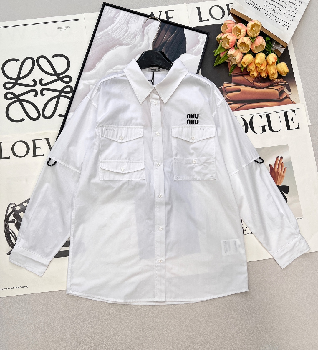 NO:739330,2026SS early spring new Miu Miu pocket workwear white shirt, who knows!  Miu Miu has taken the girly look of workwear to the extreme~ The fabric texture is crisp cotton poplin, stiff but not stiff, with a high-end drape. The oversize silhouette + dropped shoulder design are slim and free, and are super friendly to all body types. The details highlight the double breast pockets workwear style + chest letter logo, which is retro and recognizable. The pure white body instantly has a soul. How to wear it in early spring - sweet and cool college style workwear mini skirt + pile of socks + loafers -  Casual blogger-style straight-leg jeans + thick-soled boots, available immediately, will instantly fill you with an early spring atmosphere!  All three standards are complete, and the goods will be shipped in large quantities!  Size sml code M,,miumiu,versace,loafers,boots,skirts,jeans,shirts,198609092026SS早春新款Miu Miu口袋工装白衬衫,谁懂啊！Miu Miu把工装少女感玩到了极致～ 面料质感挺括棉质府绸,挺而不硬,自带高级垂感. 版型设计oversize廓形+落肩设计,显瘦又自由,对各种身材超友好. 细节亮点双胸袋工装风+胸口字母徽标,复古又有辨识度,纯白衣身瞬间有了灵魂. 早春搭法 - 甜酷学院风工装迷你裙+堆堆袜+乐福鞋 - 随性博主风直筒牛仔裤+厚底靴、现货速冲,早春氛围感直接拉满！三标齐全,大货出！ 尺码sml 编码M,,miumiu,versace,loafers,boots,skirts,jeans,shirts,,Women's clothing