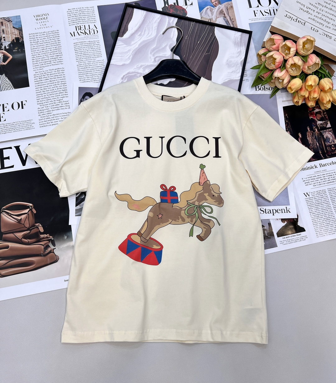 NO:739813,GUCCI circus pony printed short-sleeved T-shirt is made of custom-made combed cotton fabric. The high-weight knitting process creates a thick and crisp texture, which is delicate and soft against the skin, and will not easily deform after long-term wear. The classic cream white background is paired with a childlike circus pony print. The brand's classic logo is hidden in the smart and playful style, breaking the stereotype of luxury goods.  The loose oversize off-the-shoulder version is the same for men and women regardless of body shape. It can be worn alone to highlight a casual style, or can be used as an inner layer to unlock layering layers. Pair it with denim straight pants for a cool and casual look, or with a pleated skirt for a sweet and cool look. It can easily be worn for daily commuting and weekend outings!  The daily production rate is perfect, the three standards are complete, and the goods are delivered in large quantities!  Size sml,,gucci,versace,skirts,T-shirt,tees,t-shirt,19860909GUCCI 马戏团小马印花短袖T恤 甄选定制精梳纯棉面料,高克重针织工艺造就厚实挺括的质感,触肤细腻软糯,久穿不易变形.经典奶油白底色,搭配童趣满格的马戏团小马印花,灵动俏皮中暗藏品牌经典标识,打破奢侈品的刻板印象. 宽松Oversize落肩版型,男女同款不挑身形,既能单穿凸显随性格调,也能作为内搭解锁叠穿层次.搭配牛仔直筒裤尽显潮酷休闲,配百褶裙则甜酷交织,轻松拿捏日常通勤与周末出街的多元穿搭场景！日常出片率满分,闭眼入不亏三标齐全,大货出！ 尺码sml 编,,gucci,versace,skirts,T-shirt,tees，t-shirt,,Women's clothing