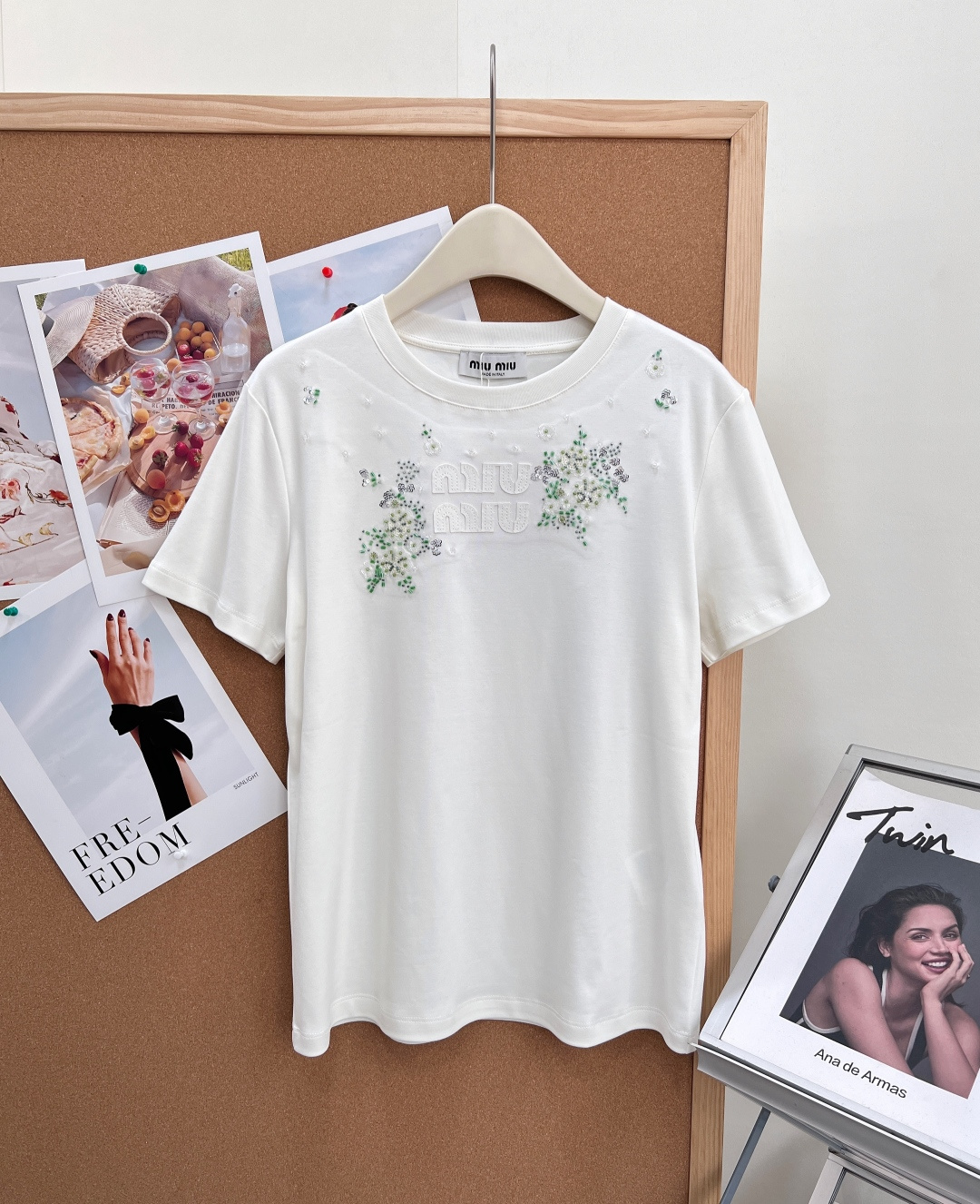NO:858017,Miu Miu 26 new beaded flower appliqué short sleeves with lettering, integrating girlish delicacy into a basic T-shirt, gentle and noble, just needed for spring and summer wear - Heavy beaded floral embroidery, completely restoring the original heavy-working craftsmanship, using a combination of three-dimensional beading + rhinestones + floral embroidery, scattered on the chest, like scattered tiny stars, full of sophistication, and full of luster under the sun.  - Patch embossed letter logo, patch embossed letters with distressed texture on the chest, low-key and unobtrusive, perfectly replicating the brand's iconic elements, with distinct texture layers, different from ordinary printed models, and the sense of luxury is instantly apparent. - Classic round neck and loose version, slightly loose H-shaped version at the front shoulder, not picky about body shape, has a good modification effect on shoulder width and arms, relaxed and comfortable in daily wear, easily create a lazy girly atmosphere. -  Made of the same high-count double-yarn combed cotton of the original style, the fabric is soft and skin-friendly, breathable and not stuffy, and the upper body is draped and stylish, and is not easy to deform and pill after long-term wear. - The neckline adopts reinforced binding technology, the wiring is neat, and the beads are firm and not easy to fall off. Everything from details to hardware matches the quality of the original. - The milky white color is gentle and pure, with a rich atmosphere, suitable for daily commuting, afternoon tea dates, and looks great when paired with skirts and jeans. -  The classic black color is cool and slimming, and the sweet and cool style can be directly adapted. It is suitable for daily outings, shopping and shopping. It is versatile and has a full slimming effect. Complete with three standards, large quantities of goods!  Size sml,,miumiu,skirts,jeans,T-shirt,tees,t-shirt,19860909Miu Miu 26新款钉珠花卉贴布字母短袖,把少女精致感融入基础款T恤,温柔又显贵,春夏穿搭的氛围感刚需 -重工钉珠花卉刺绣,完整还原原版重工工艺,采用立体钉珠+水钻+花卉刺绣组合,错落点缀在胸前,像散落的细碎星光,精致度拉满,阳光下光泽感十足. -贴布浮雕字母标识,胸前做旧质感的贴布浮雕字母,低调不张扬,完美复刻品牌标志性元素,质感层次分明,区别于普通印花款,高级感瞬间显现. -经典圆领宽松版型,正肩微宽松的H型版型,不挑身形,对肩宽、手臂有很好的修饰效果,日常穿着松弛自在,轻松打造慵懒少女氛围. - 采用原版同款高支双纱精梳棉,面料软糯亲肤,透气不闷汗,上身垂坠有型,久穿不易变形起球. - 领口采用加固包边工艺,走线工整,钉珠牢固不易脱落,从细节到五金全部对标原版品质. - 奶白色温柔纯净,自带千金氛围感,适配日常通勤、下午茶约会,搭配半裙、牛仔裤都超显气质. - 经典黑清冷显瘦,甜酷风格直接拿捏,适配日常出街、逛街探店,百搭不出错,显瘦效果拉满.三标齐全,大货出！ 尺码sml,,miumiu,skirts,jeans,T-shirt,tees，t-shirt,,Women's clothing