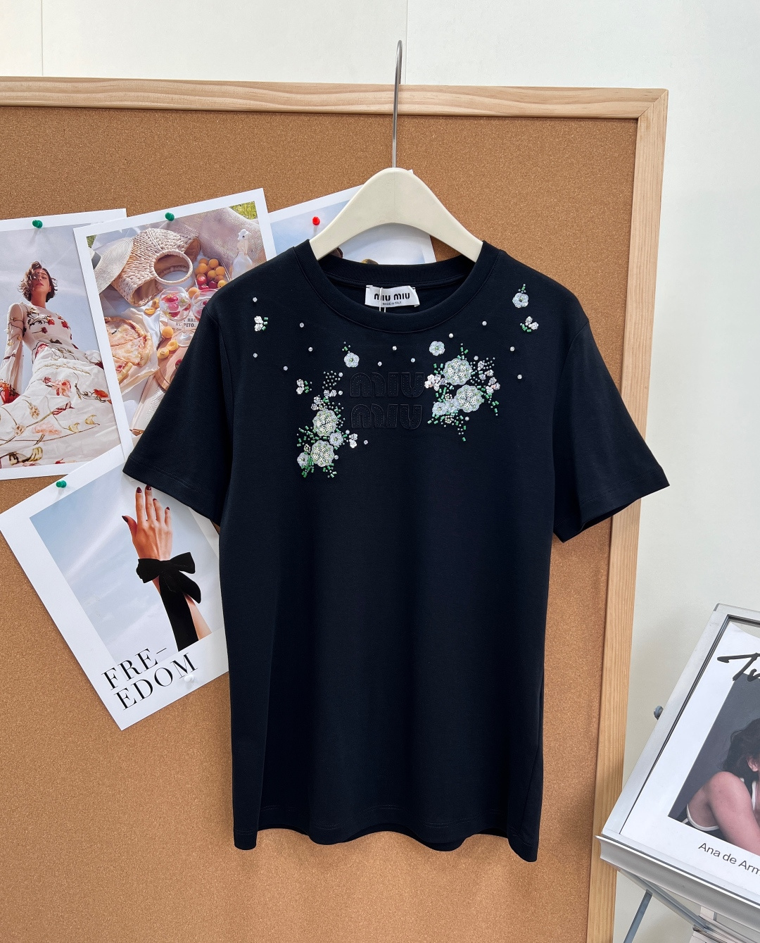 NO:857914,Miu Miu 26 new beaded flower appliqué short sleeves with lettering, integrating girlish delicacy into a basic T-shirt, gentle and noble, just needed for spring and summer wear - Heavy beaded floral embroidery, completely restoring the original heavy-working craftsmanship, using a combination of three-dimensional beading + rhinestones + floral embroidery, scattered on the chest, like scattered tiny stars, full of sophistication, and full of luster under the sun.  - Patch embossed letter logo, patch embossed letters with distressed texture on the chest, low-key and unobtrusive, perfectly replicating the brand's iconic elements, with distinct texture layers, different from ordinary printed models, and the sense of luxury is instantly apparent. - Classic round neck and loose version, slightly loose H-shaped version at the front shoulder, not picky about body shape, has a good modification effect on shoulder width and arms, relaxed and comfortable in daily wear, easily create a lazy girly atmosphere. -  Made of the same high-count double-yarn combed cotton of the original style, the fabric is soft and skin-friendly, breathable and not stuffy, and the upper body is draped and stylish, and is not easy to deform and pill after long-term wear. - The neckline adopts reinforced binding technology, the wiring is neat, and the beads are firm and not easy to fall off. Everything from details to hardware matches the quality of the original. - The milky white color is gentle and pure, with a rich atmosphere, suitable for daily commuting, afternoon tea dates, and looks great when paired with skirts and jeans. -  The classic black color is cool and slimming, and the sweet and cool style can be directly adapted. It is suitable for daily outings, shopping and shopping. It is versatile and has a full slimming effect. Complete with three standards, large quantities of goods!  Size sml,,miumiu,skirts,jeans,T-shirt,tees,t-shirt,19860909Miu Miu 26新款钉珠花卉贴布字母短袖,把少女精致感融入基础款T恤,温柔又显贵,春夏穿搭的氛围感刚需 -重工钉珠花卉刺绣,完整还原原版重工工艺,采用立体钉珠+水钻+花卉刺绣组合,错落点缀在胸前,像散落的细碎星光,精致度拉满,阳光下光泽感十足. -贴布浮雕字母标识,胸前做旧质感的贴布浮雕字母,低调不张扬,完美复刻品牌标志性元素,质感层次分明,区别于普通印花款,高级感瞬间显现. -经典圆领宽松版型,正肩微宽松的H型版型,不挑身形,对肩宽、手臂有很好的修饰效果,日常穿着松弛自在,轻松打造慵懒少女氛围. - 采用原版同款高支双纱精梳棉,面料软糯亲肤,透气不闷汗,上身垂坠有型,久穿不易变形起球. - 领口采用加固包边工艺,走线工整,钉珠牢固不易脱落,从细节到五金全部对标原版品质. - 奶白色温柔纯净,自带千金氛围感,适配日常通勤、下午茶约会,搭配半裙、牛仔裤都超显气质. - 经典黑清冷显瘦,甜酷风格直接拿捏,适配日常出街、逛街探店,百搭不出错,显瘦效果拉满.三标齐全,大货出！ 尺码sml,,miumiu,skirts,jeans,T-shirt,tees，t-shirt,,Women's clothing