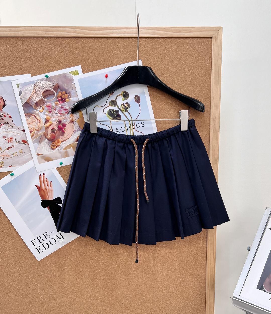 NO:872611,Miu Miu navy drawstring pleated skirt. Orthodox school-style skirt for girls. Classic navy dyed fabric, low saturation and deep blue to match the skin tone. The yellow leather upper body also comes with a cool white leather filter, which is retro and age-reducing. The slim and light worsted fabric is stiff and not easy to collapse and deform. The pleats are long-lasting and neat. It can be worn in all seasons. In early autumn, it can be paired with a plaid shirt to complete the atmosphere.  The elasticated high-waisted drawstring waistband and contrasting brown and white woven drawstring are the finishing touches. It does not pick up on the waistline, and the elasticity is comfortable and does not tighten the abdomen. The uniform and fine three-dimensional pleating process makes each pleat line neat and stylish. It has a fluffy A-line version, hiding the crotch and flesh, and optimizing the line of the lower body.  The short skirt has just the right length and comes with a safety and anti-exposure lining, making it hassle-free for daily commuting and school trips. The low-key brand logo embroidered in the same color on the side of the skirt is simple and refined, weakening the sense of exaggeration, and perfectly fits the gentle and girly tone of miumiu. Complete with three standards, large quantities of goods!  Size sml,,miumiu,skirts,shirts,19860909Miu Miu藏青抽绳百褶短裙.正统少女学院风短裙.经典藏青定染面料,低饱和深蓝巨衬肤色,黄皮上身也自带冷白皮滤镜,复古减龄不挑人.垂顺轻薄精纺面料,挺括不易软塌变形,褶皱持久利落,四季都能穿,早秋搭配格纹衬衫成套氛围感直接拉满. 松紧高腰抽绳腰头,棕白撞色编织抽绳是点睛设计,不挑腰围,松紧自在不勒腹；均匀细密立体压褶工艺,每一道褶线工整有型,自带蓬松A字版型,藏胯遮肉,优化下半身线条. 短款裙长恰到好处,自带安全防走光内衬,日常通勤、上学出行无负担；裙侧低调同色刺绣品牌标识,简约精致,弱化浮夸感,完美契合miumiu温柔少女调性.三标齐全,大货出！ 尺码sml,,miumiu,skirts,shirts,,Women's clothing