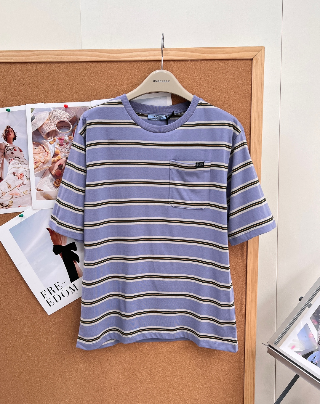 NO:909474,PRADA's new horizontal striped patch pocket round neck short-sleeved T-shirt is made of high-count combed cotton jersey, which has been treated with liquid ammonia mercerization pre-shrinking and washing process. The fabric surface is smooth and matte, resists deformation and has excellent color fastness.  The fabric adopts a multi-color horizontal stripe yarn-dyed weaving process. The light purple base is matched with evenly spaced stripes in three colors of off-white, olive green and fine gold. The strips are accurately aligned and there is no misalignment. The version adopts a slightly loose and dropped shoulder basic silhouette. The neckline is a high-elastic tube woven rib collar. The inner side uses a ring-stitched lock collar process to long-term resistance to stretch and looseness.  A square patch pocket of the same fabric is sewn on the left chest of the front panel. The mouth of the bag is reinforced with double-needle flat-turn stitching. A woven brand logo is sewn on the outside of the bag body. The shoulder seams and side seams adopt four-thread overlocking technology. The cuffs and hem are unified with double-needle flat-turn hems.  , the whole back panel is designed with no divisions to simplify the structural lines, and integrates the classic yarn-dyed stripe craftsmanship, the standardized sewing structure of luxury garments and the casual off-shoulder version, taking into account daily practical breathability and neat and fine garment craftsmanship details!  Complete with three standards, ready for delivery!  Size sml code,,prada,T-shirt,tees,t-shirt,19860909PRADA新款横条纹贴袋圆领短袖T恤,采用高支精梳棉平纹针织汗布,经液氨丝光预缩水洗工艺处理,布面柔滑哑光、抗形变且色牢度表现优异 面料采用多色横向间条色织织造工艺,浅紫基底搭配米白、橄榄绿、细金三色均匀等距条纹,条带对位精准无错格.版型采用微宽松落肩基础廓形,领口为本料高弹筒织罗纹圆领,内侧采用环缝锁领工艺,长效抵御拉伸松垮 前片左胸缝制同面料方形贴袋,袋口双针平车压线加固,袋身外侧缝制织唛品牌标识标；肩缝、侧缝采用四线锁边包缝工艺,袖口与下摆统一执行折边双针平车收缝,后片整片无分割裁片设计简化结构线条,将经典色织间条工艺、奢品成衣标准化缝制结构与休闲落肩版型融合,兼顾日常实穿透气性与规整精细的成衣工艺细节！三标齐全,现货发！ 尺码sml 编码,,prada,T-shirt,tees，t-shirt,,Women's clothing