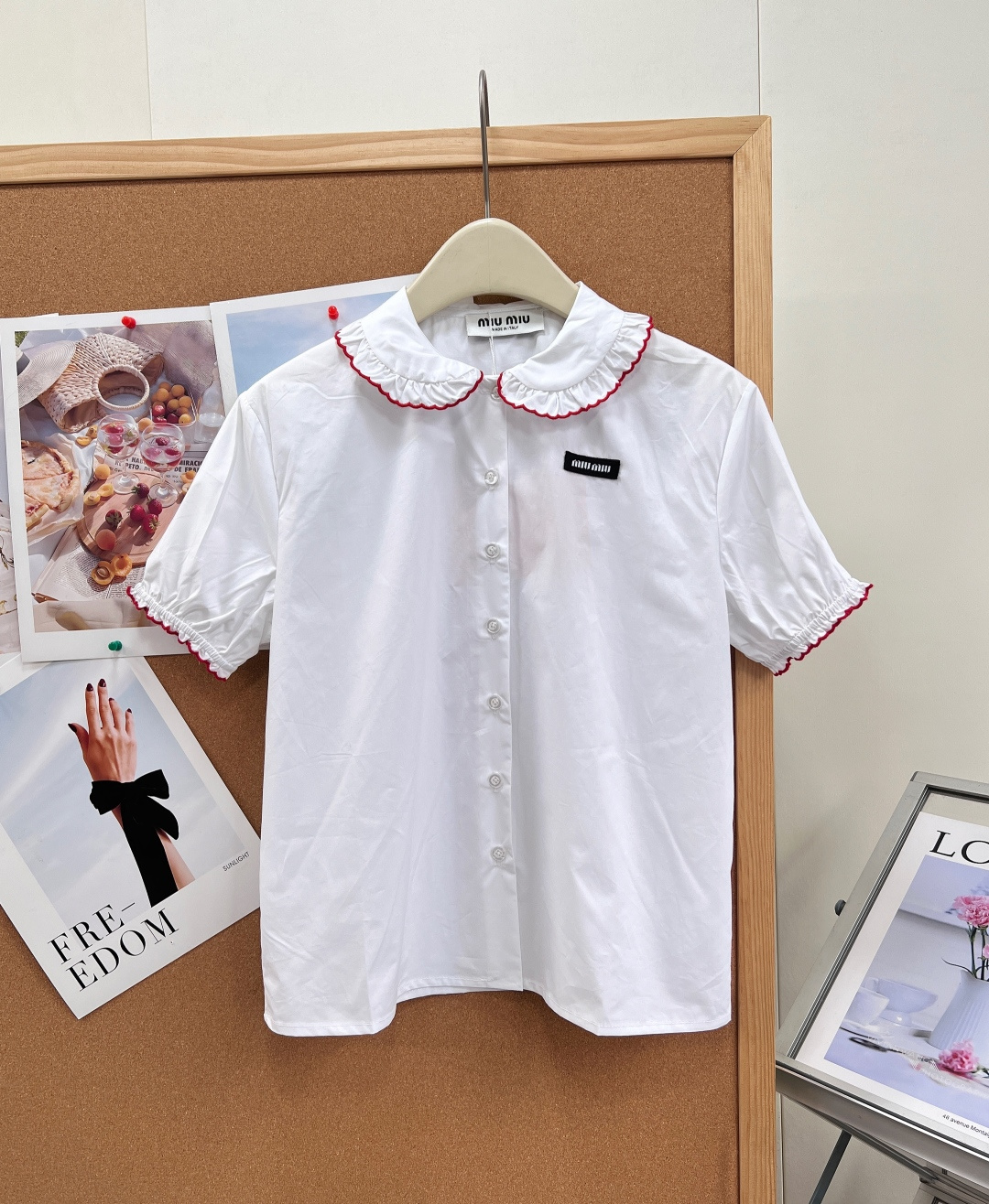 NO:923342,MIUMIU Girly Style Doll Collar Ruffled Short-Sleeved Shirt. French sweet elements that will always make your heart beat~ White main color + red ruffles, doll collar design is sweet and playful, the brand logo on the chest is very recognizable, puff sleeves are full of retro feel, you can easily control the college style or sweet girl style, match it with pleated skirt or high-waisted pants, and you will be full of girly feeling~ The doll collar is paired with burgundy contrasting wavy ruffle piping, sweet but not greasy  Puffed short sleeves + lace cuffs of the same color, gentle and slimming. Pearl-textured buttons on the placket + brand woven label on the chest, low-key imprinting of the brand style. Crisp and smooth cotton fabric, the upper body is breathable and not soft or wrinkled. The upper body has a gentle and rich family look, which directly makes you look younger. Wear it alone, it is clean and refreshing, and it looks very elegant when paired with skirts, jeans, and suits. Suitable for daily commuting, dating, afternoon tea, and traveling for photos.  Pure milky white background, burgundy contrasting lace accents, a retro college feel, short-sleeved puff sleeve design, refreshing and not stuffy in summer. Comes with gentle filter when worn. Classic white and red color combination, girly and elegant. Can be salty or sweet. Miu-like~ Complete with three standards, large quantity!  Size sml code,,miumiu,skirts,jeans,shirts,T-shirt,business suit,19860909MIUMIU 少女风娃娃领荷叶边短袖衬衫 永远心动的法式甜美元素～ 白色主色+红色荷叶边,娃娃领设计甜美俏皮,胸前品牌徽标超有辨识度,泡泡袖复古感满满,学院风or甜妹风都能轻松驾驭,搭配百褶裙或高腰裤,元气少女感直接拉满～ 娃娃领搭配酒红色撞色波浪荷叶边滚边,甜而不腻 泡泡短袖+同色系花边收口,温柔又藏肉显瘦 门襟珍珠质感纽扣+胸口品牌织标,低调刻印品牌格调 挺括顺滑的棉质面料,上身透气不软塌、不易皱 上身就是温柔富家千金感,减龄感直接拉满 单穿干净清爽,搭配半裙、牛仔裤、西装都超有气质 日常通勤、约会下午茶、出游拍照都适配 纯净奶白底色,酒红撞色花边点睛,自带复古学院感,短袖泡泡袖设计,夏天清爽不闷热 穿上自带温柔滤镜 经典白红配色,少女感与优雅兼具 可盐可甜 miu里miu气～三标齐全,大货出！ 尺码sml 编码,,miumiu,skirts,jeans,shirts,T-shirt,business suit,,Women's clothing