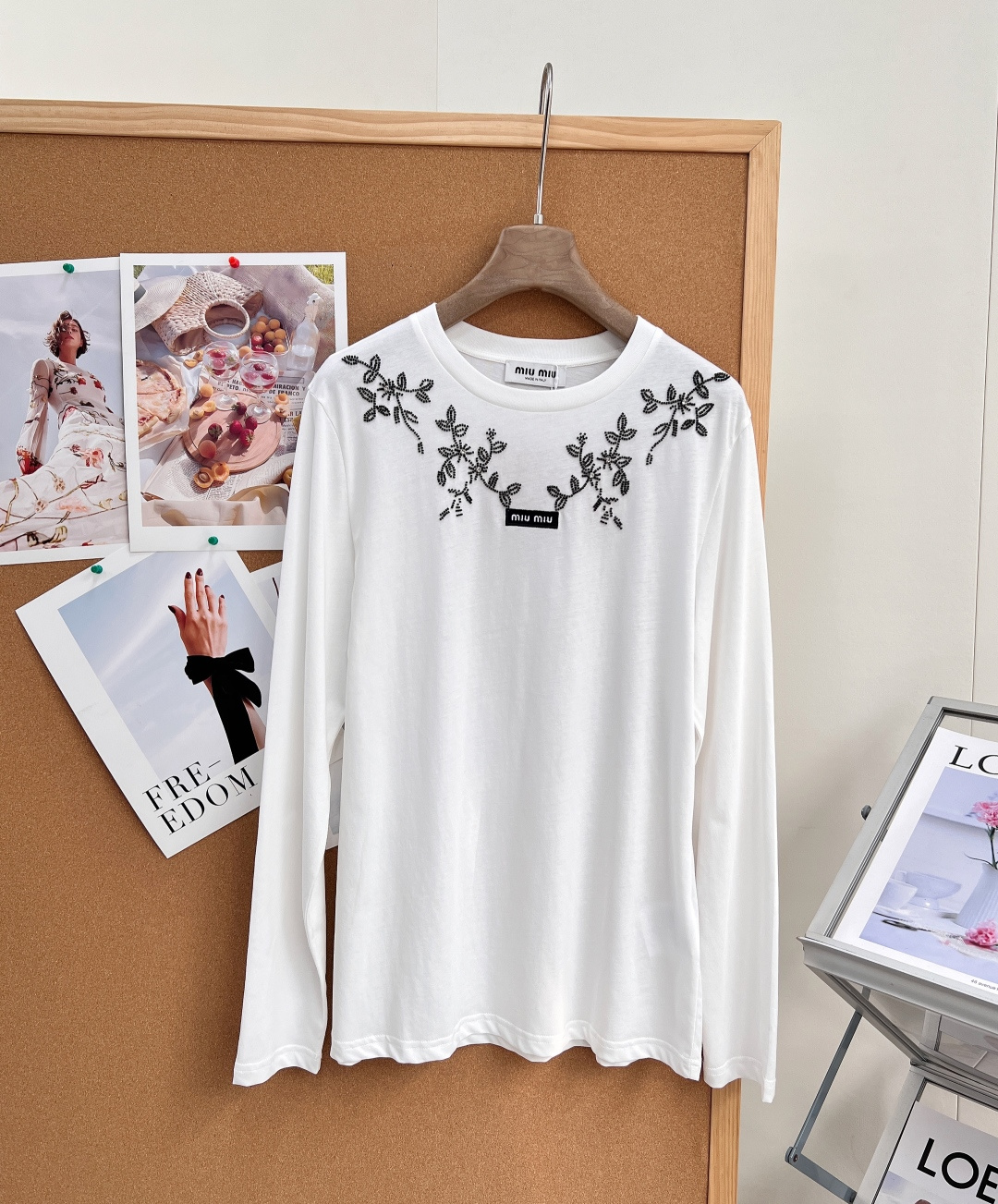 NO:952869,Miu Miu26SS vine beaded embroidery long-sleeved T-shirt has an early autumn atmosphere as a base layer top. The classic black and white two-tone color will never go out of style. The neckline is surrounded by exquisite vine flower beaded embroidery. It is sweet but not vulgar, and directly brings out the elegance of a retro girl.  We select soft, waxy, high-count, skin-friendly fabrics, which are washed and softened. They feel delicate and light, breathable and not stuffy. They are refreshing and comfortable to wear alone in early autumn. In autumn and winter, they will not be bloated at all when worn under suits and coats, and they will not pill and deform easily after long-term wear.  Basic and classic round neck, it fits the neck without being tight; extended floral beading embroidery on both sides of the neckline, the beading is dense and three-dimensional, the branches and leaves pattern is smart and elegant, with just the right sense of sophistication without being overly exaggerated; the mini woven logo on the chest is a low-key finishing touch, full of details.  The fitted and neat long-sleeved version just modifies the muscles of the arms and optimizes the lines of the shoulders and arms; the straight-fitting body is neither tight nor loose and draggy. It looks good when tucked in at the corners and naturally hanging down, and can easily optimize body proportions.  The pure white is gentle and sweet, while the black is restrained and elegant; worn alone with a skirt and jeans, it is a cute school girl style; layered with a small jacket, windbreaker, and suit, it has a gentle and retro atmosphere, suitable for commuting, dating, and afternoon tea. Complete with three standards, large quantities of goods!  Size sml code,,miumiu,skirts,jeans,jackets & coats,tees,t-shirt,business suit,19860909Miu Miu26SS藤蔓钉珠刺绣长袖T恤早秋氛围感打底上衣,经典黑白双色永不过时,领口环绕精致藤蔓花卉钉珠刺绣,甜而不俗,把复古少女优雅感直接拉满. 甄选软糯高支亲肤面料,经过水洗柔化处理,触感细腻轻盈,透气不闷,早秋单穿清爽舒适,秋冬作为西装、大衣内搭完全不会臃肿,久穿不易起球变形. 基础经典小圆领,贴合脖颈不紧绷；领口两侧延伸式花卉钉珠刺绣,珠绣密实立体,枝叶花纹灵动雅致,精致感恰到好处,不会过度浮夸；胸口迷你织唛logo低调点睛,细节拉满. 合身利落长袖版型,刚好修饰手臂拜拜肉,优化肩臂线条；直筒合身衣身,不紧绷不宽松拖沓,日常塞衣角、自然垂落都好看,轻松优化身材比例. 纯净白温柔清甜,黑色内敛雅致；单穿搭配半身裙、牛仔裤是乖巧学妹风；叠穿小香外套、风衣、西装,温柔复古氛围感十足,通勤、约会、下午茶全场景适配.三标齐全,大货出！ 尺码sml 编码,,miumiu,skirts,jeans,jackets & coats,tees，t-shirt,business suit,,Women's clothing