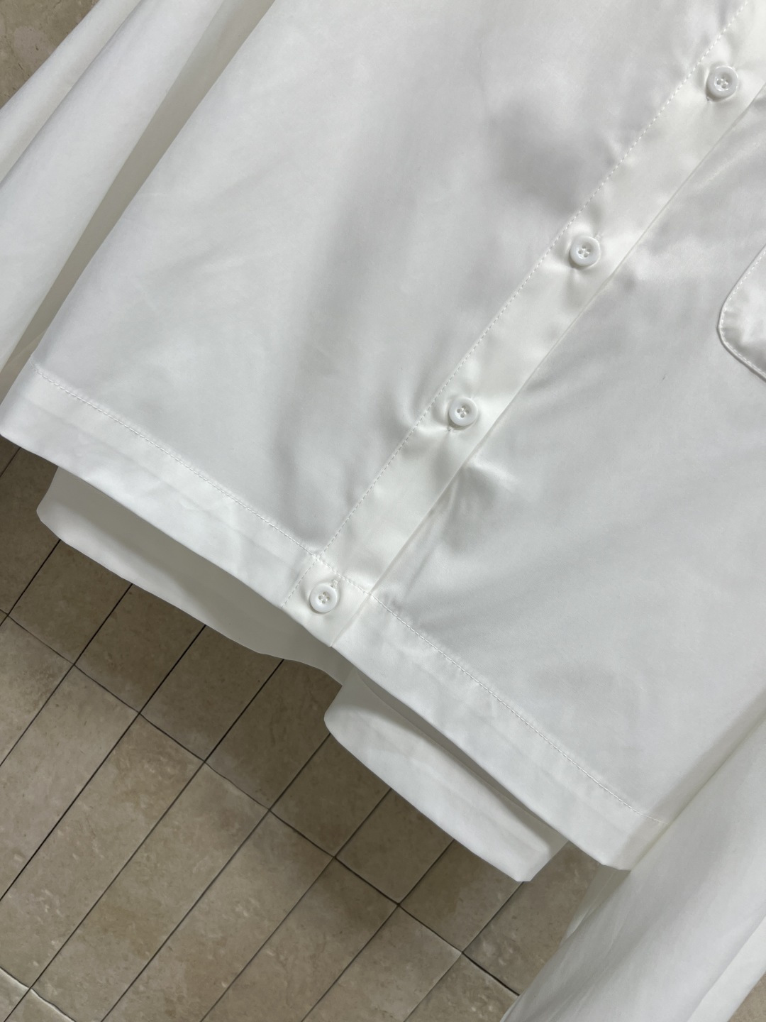 D家 26春夏新款 白色刺绣口袋衬衫 利落翻领+前短后长剪裁 面料透气挺括 宽松版型 口袋处的立体贴花是