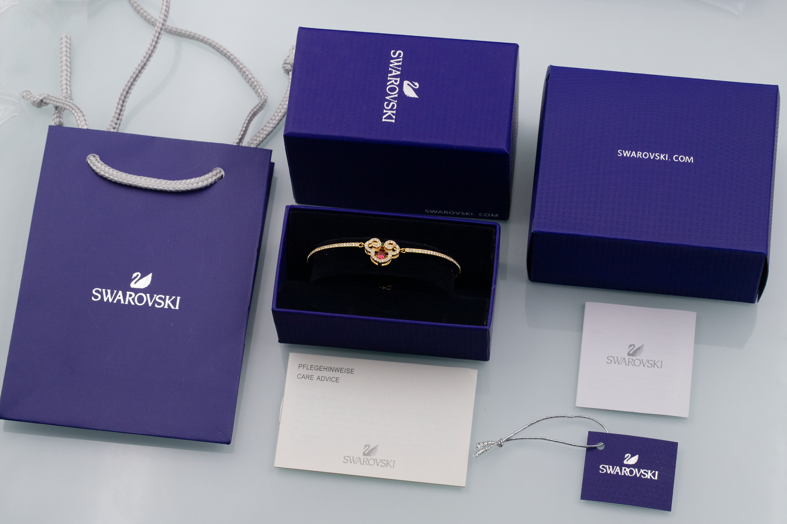 批115 👍🏻【新品】施华洛世奇Gratia 柿柿如意 手镯 女
😍😍😍红色服装搭配，美绝了！
💥含包装💥  🔥量大私聊！
这款耀眼的镀金色调手镯的设计灵感来自故宫博物院的馆藏文物。这款手
镯以密镶仿水晶金属带形成代表性的「如意」吉祥图案,中心饰有一颗美
丽的红色 Dancing Stone,最后以一个经典的龙虾扣扣紧链条。是送给自
己或朋友的文雅礼物之选。这款手镯是我们与故宮廷文化共同设计,属
于 Gratia产品系列。
📌编号:5622090
📌尺寸:5.9*4-可调节