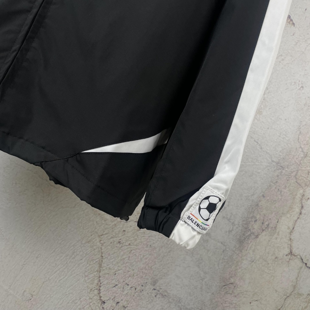 💰175 【原版】款号：AB035
【上新】Balenciaga丨 巴黎世家 23SS 联名足球背后字母印花冲锋衣立领外套

引入足球元素 黑白配色字母印花设计 宽松版型 双向拉链闭合 前胸sponsor刺绣徽章 后背压印徽标及球队号码 动感活力的一款冲锋衣

os宽松版型 双层用料 整件用布5米 成本极高 由47块裁片组成  出品极慢 绝对重工 整件车缝止口需要车的很均匀平整否则就拼不起来成品，特别是不规则的拐弯处还得左右对称裁片，如果线路没控制好很容易出现裁片长短 还有前幅印花位需左右平齐对称 左袖口带有新款定制足球刺绣徽章

颜色：黑
Size：S M L XL 现货秒发 详细尺码可查图9
