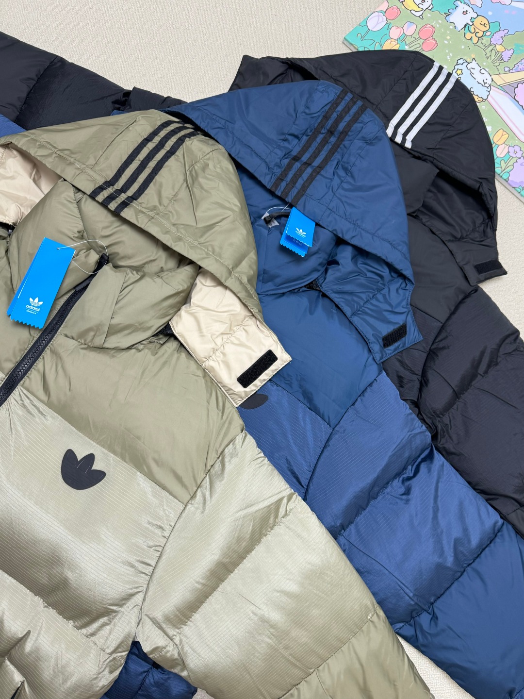P200💰
❄️入冬刚需！Adidas三叶草羽绒棉服，暖到犯规还巨时髦！

怕羽绒服太厚重？这件Adidas三叶草拼接羽绒棉服给你“轻暖潮”三重体验！

三款配色闭眼挑：

• 卡其拼接款，复古感拉满，搭卫衣牛仔裤就是美式街头靓仔；

• 深蓝款沉稳又高级，上班逛街都能hold住；

• 经典黑款百搭到天际，什么风格都能无缝衔接～

连帽设计防风又显脸小，棉填充保暖不压身，日常通勤、周末遛弯穿它就对了！胸前低调三叶草标，细节处藏满质感，穿上它，在寒风里也能潮得毫不费力🔥

别让臃肿毁了你的冬日造型，这件“保暖时髦二合一”的棉服，现在不冲等着挨冻吗？